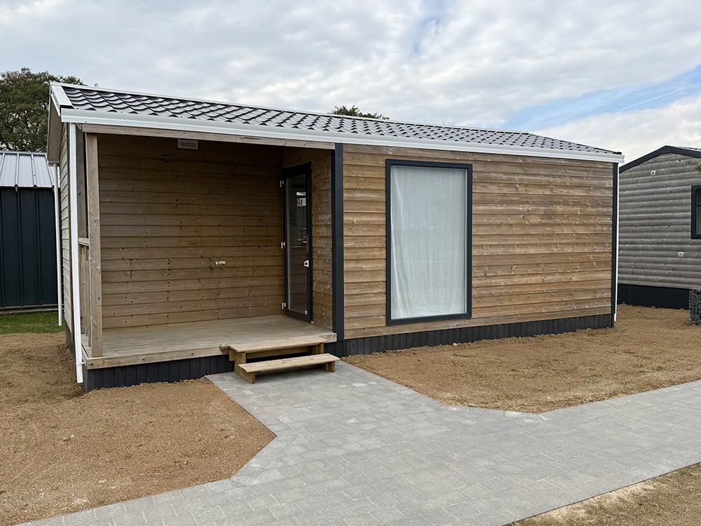 Modern indoor space with large glass doors, lush greenery, and a cozy seating area visible beyond.