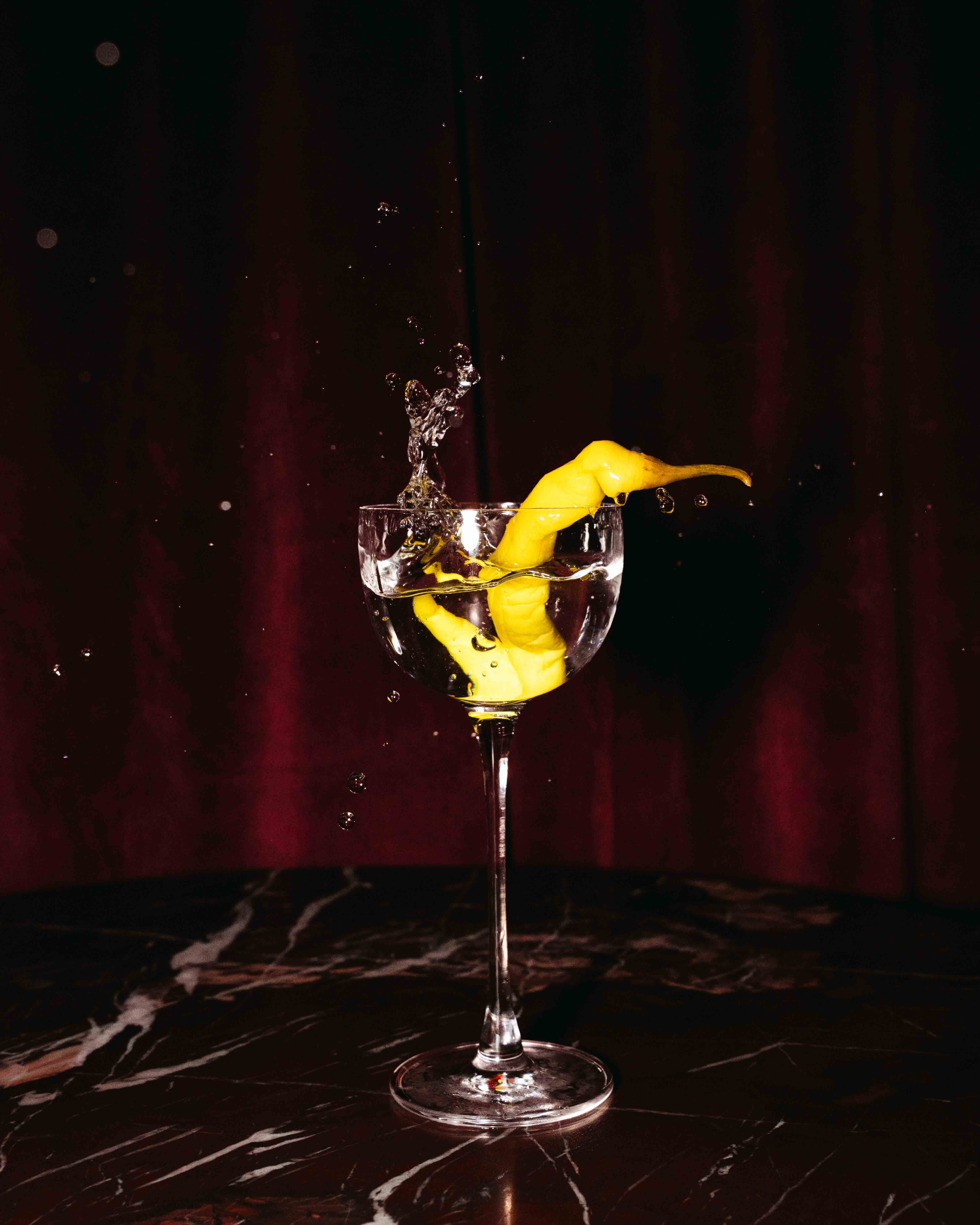 Wooden outdoor table set with multiple plates of food, including dips, salads, potatoes with cheese, and glasses of water, with hands reaching in to eat.