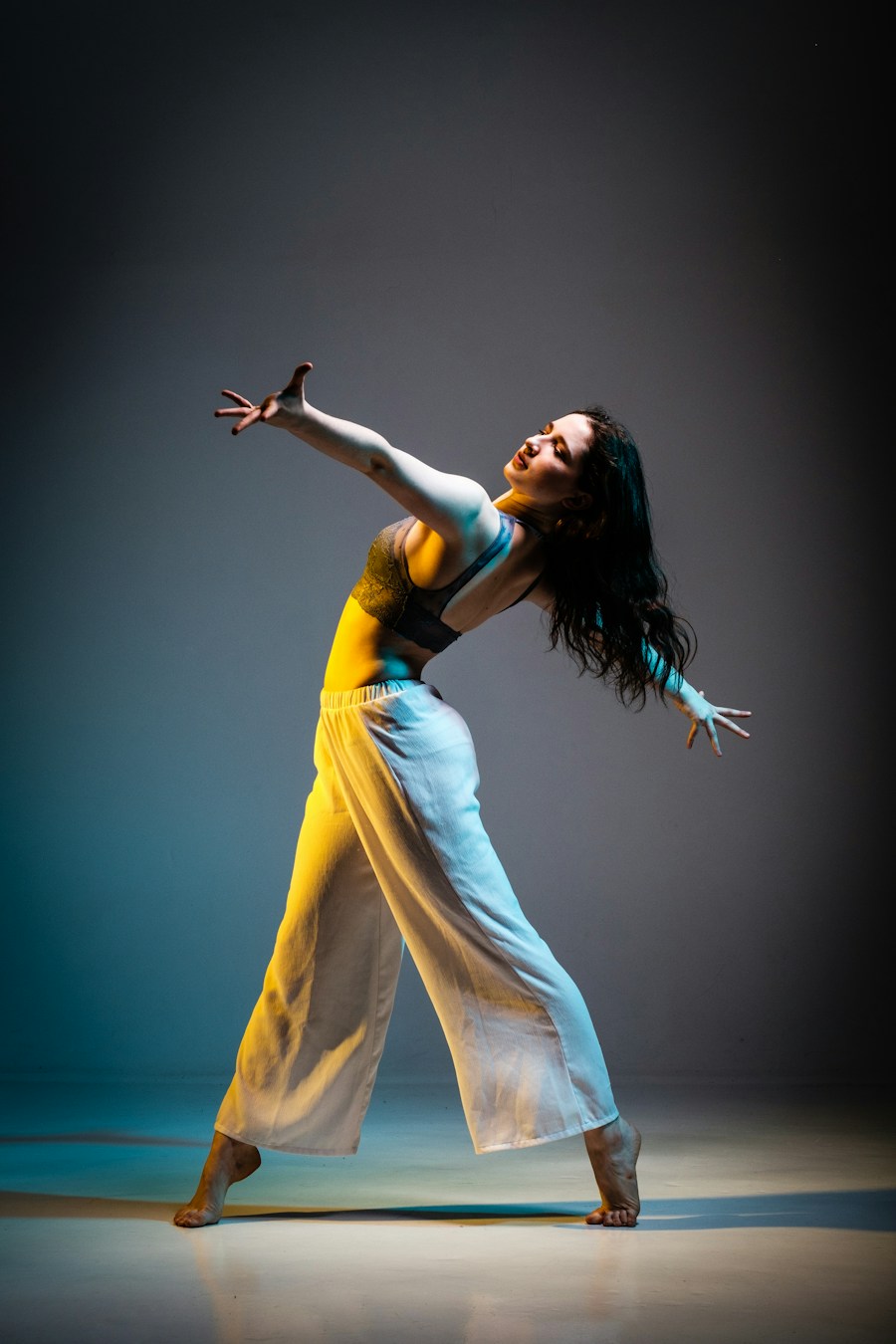 A contemporary dancer in yellow and white extending her arms in a flowing movement