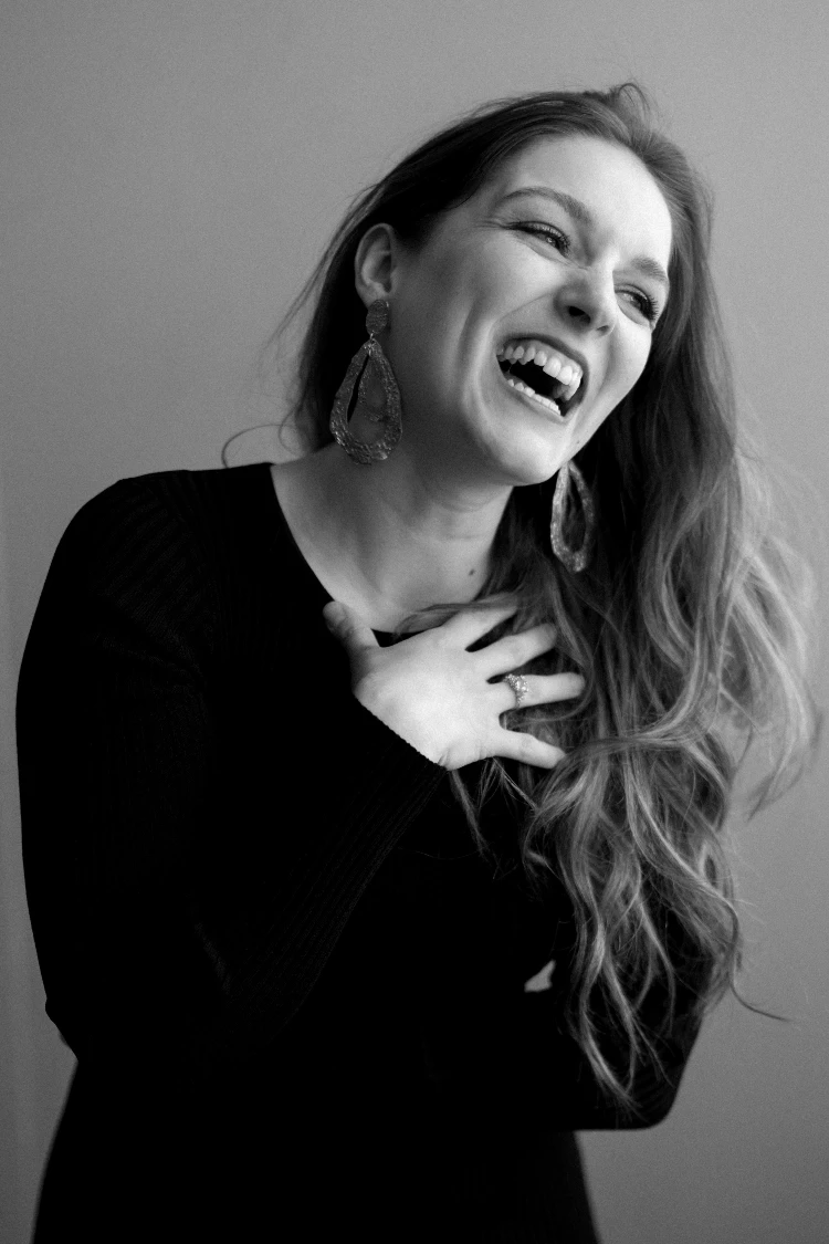 Laughing woman in black dress, showcasing luxury selflove boudoir photography.