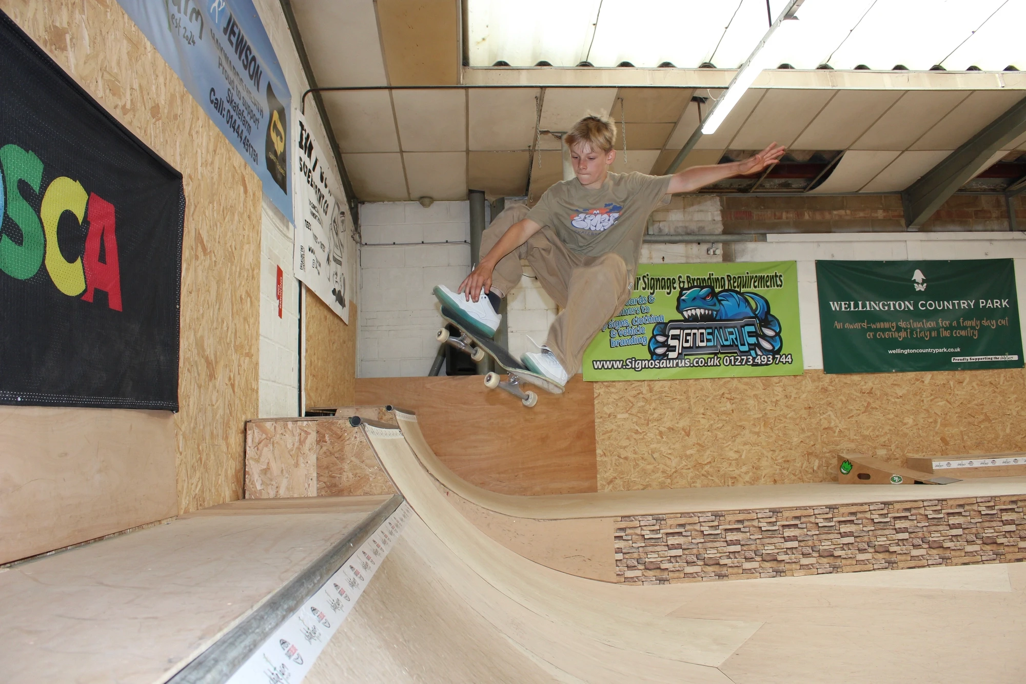 Young skateboarder performing a grab trick off the mini ramp at The Skate Farm indoor skatepark in Haywards Heath