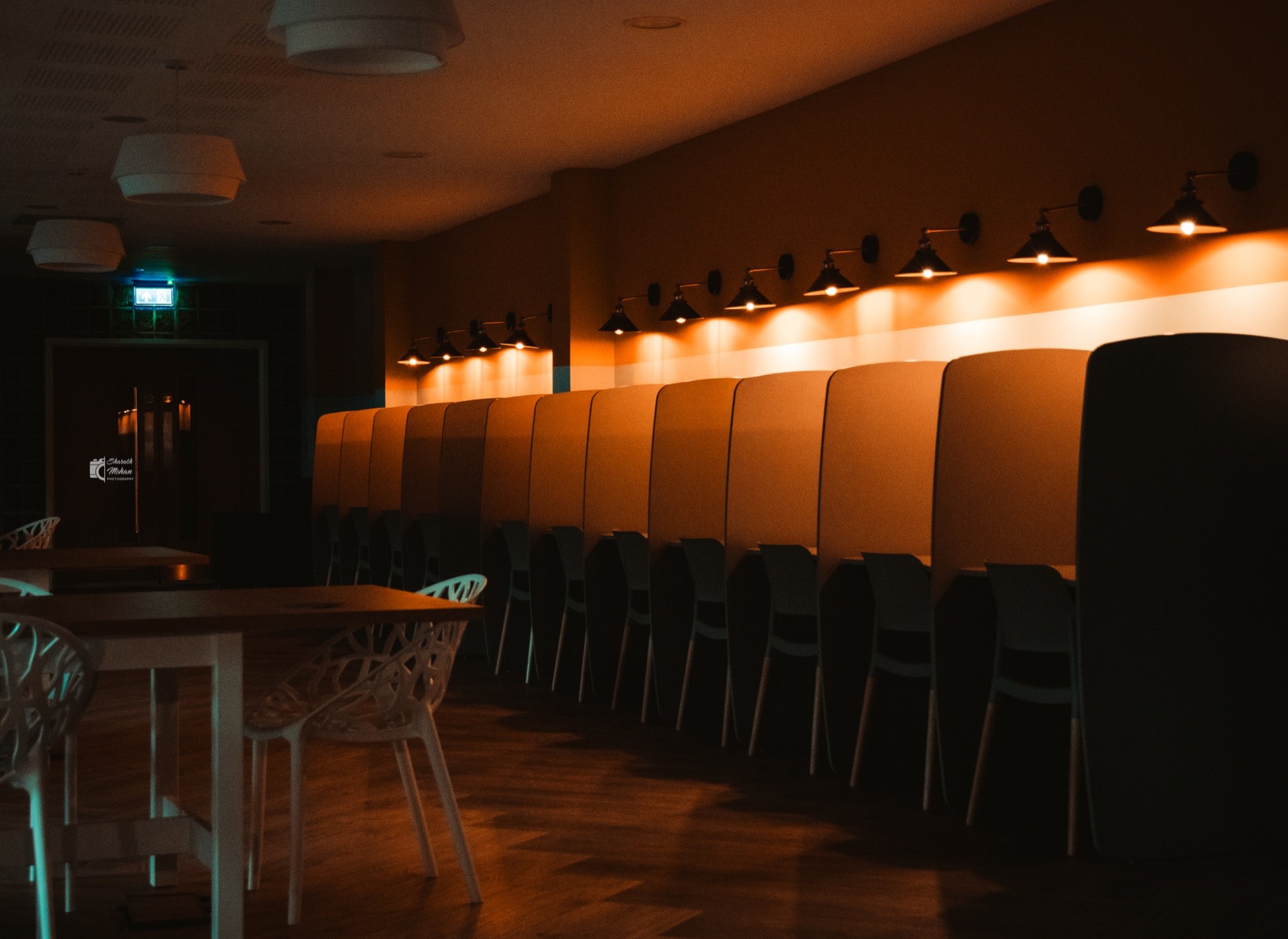 A long row of booths lit by warm lamps in a dark interior.