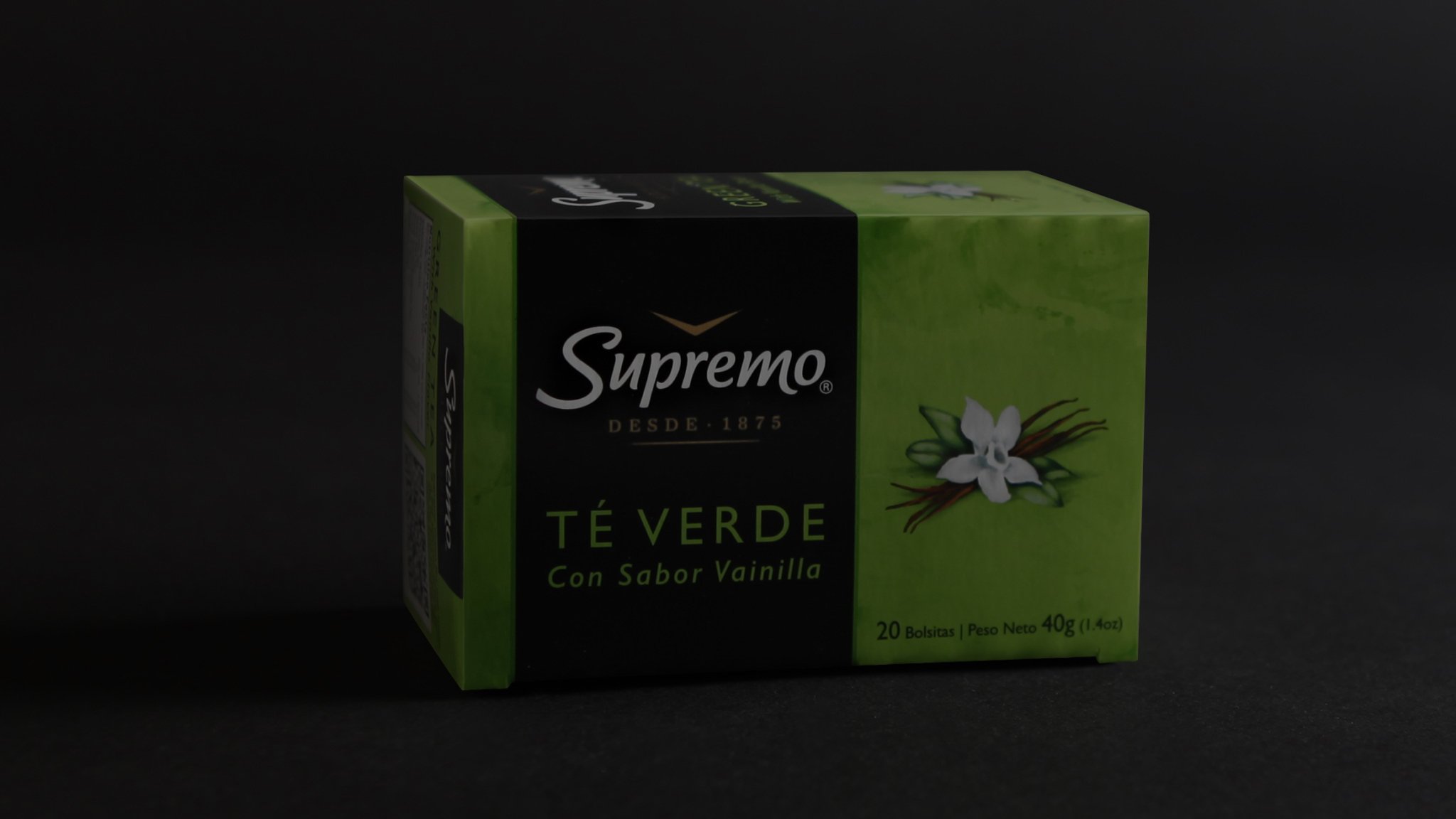 A box of Supremo Té Verde Con Sabor Vainilla is shown against a dark background. The packaging is green and black, featuring a vanilla flower image.