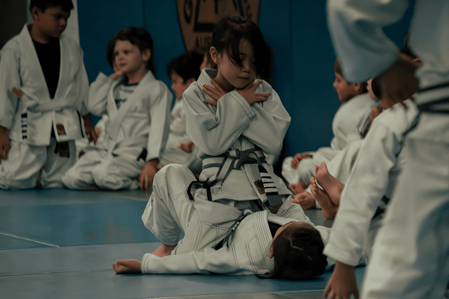 Young students sitting on the mat during a kids’ Jiu Jitsu session