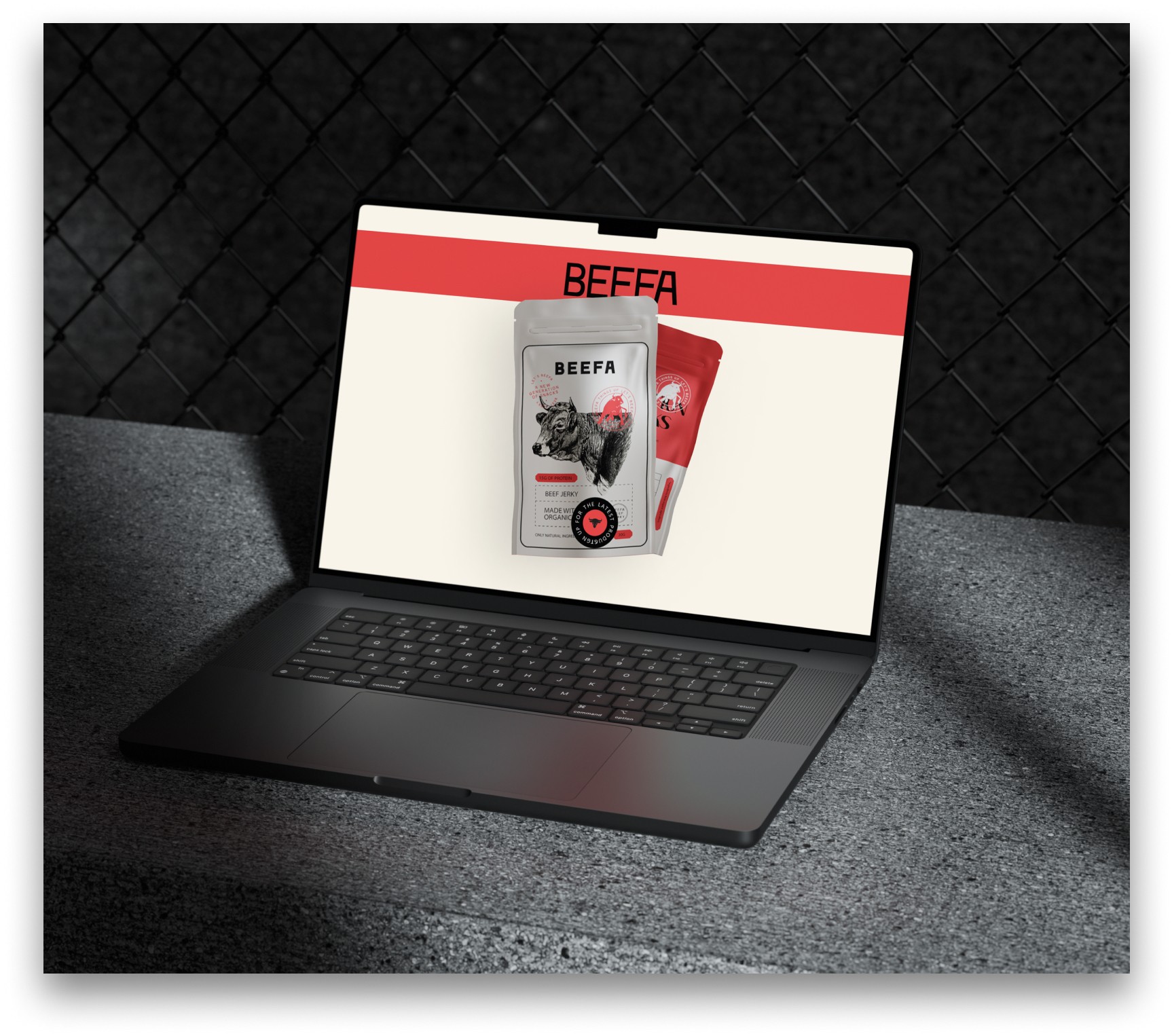 A laptop showcases the Beefa jerky website designed by The Editor Suite . The screen features product packaging against a red and off-white color scheme. The laptop rests on a textured gray surface in front of a chain-link fence, adding a touch of urban grit.