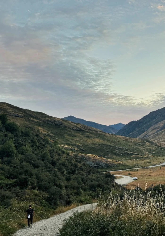 A figure walking a long road toward a distant mountain.