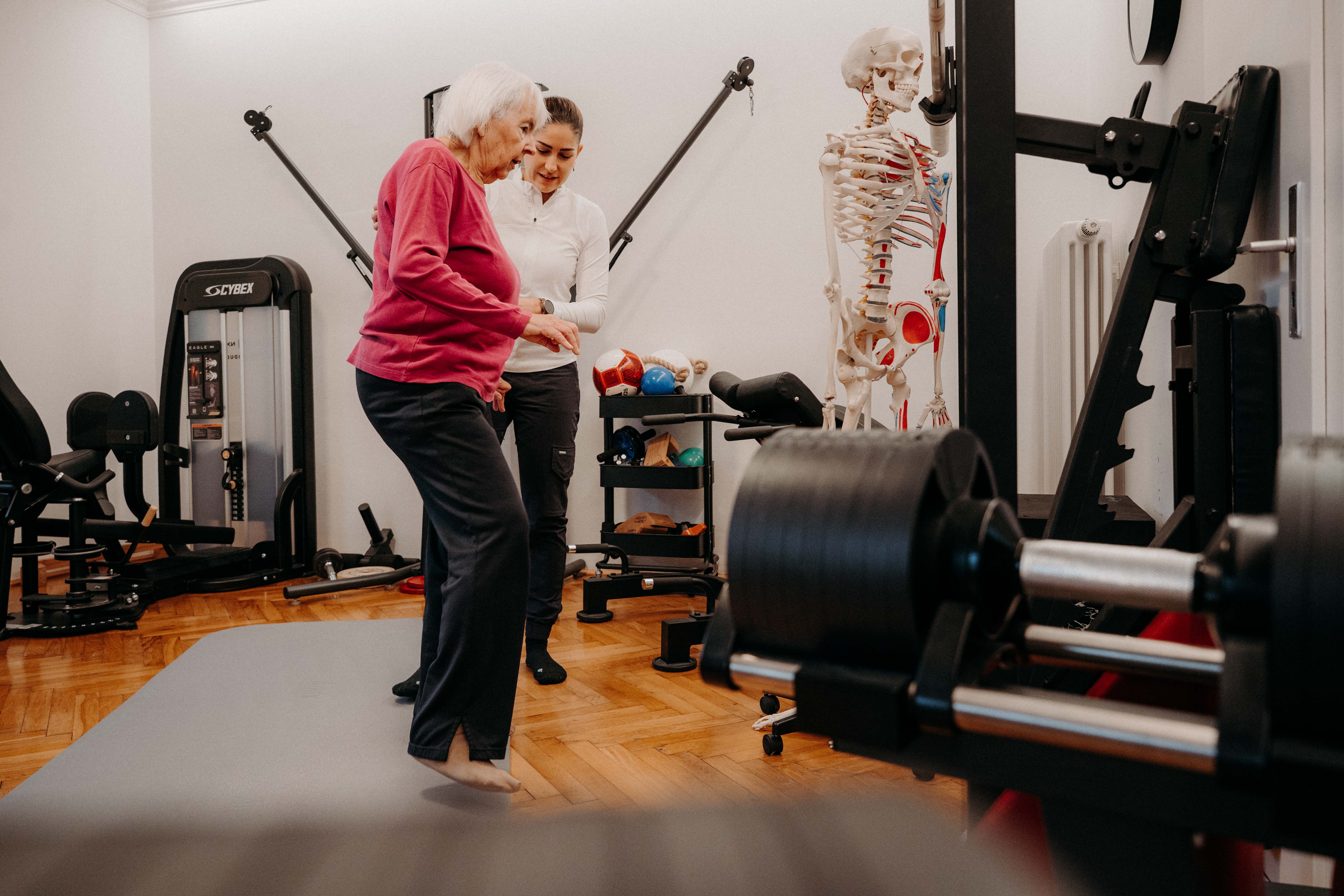 Ältere Frau trainiert mit Physiotherapeutin in einem Fitnessstudio, um ihre Gesundheit zu verbessern.