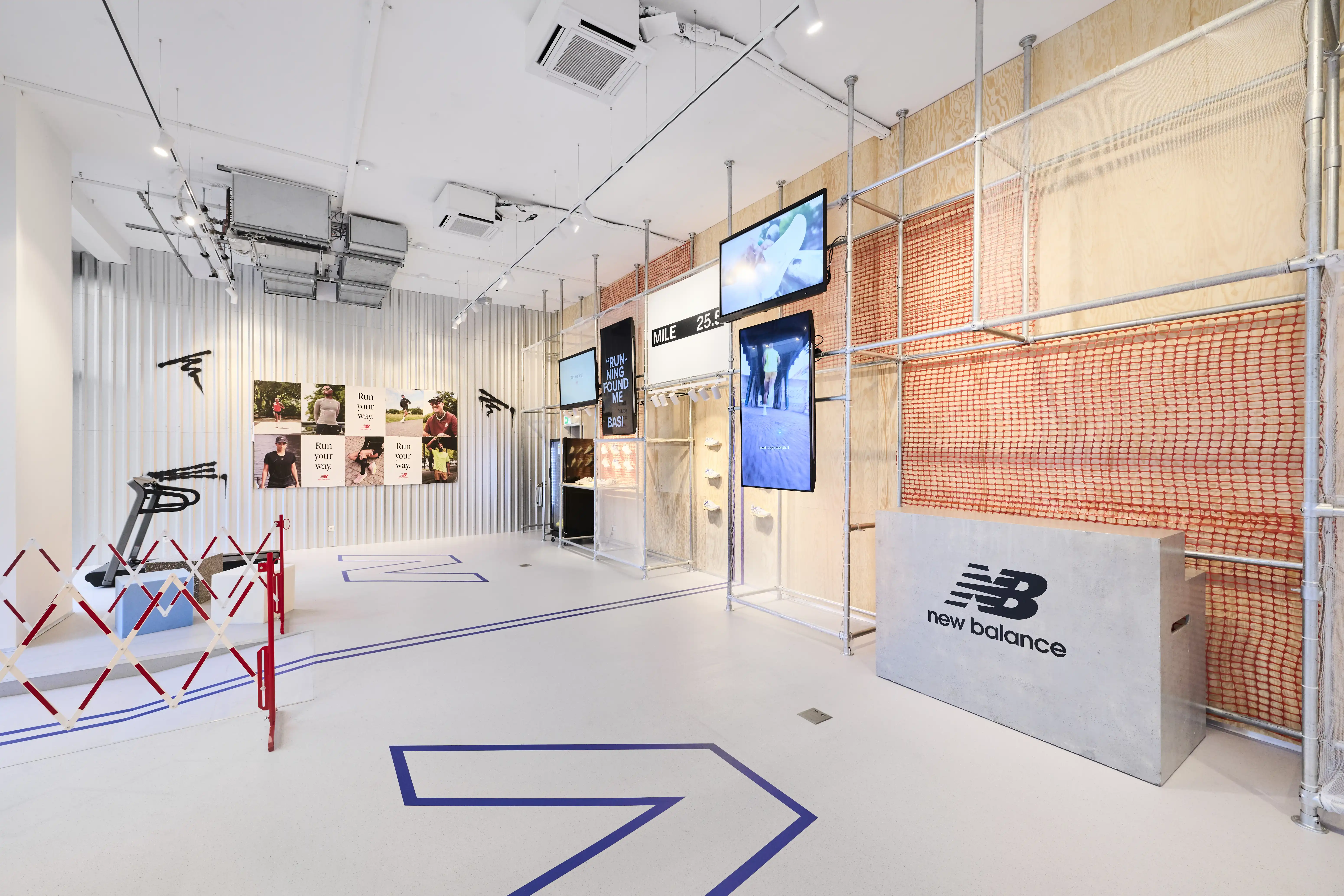 Concrete-look New Balance counter in front of scaffolding and orange netting at the Highsnobiety x New Balance pop-up.