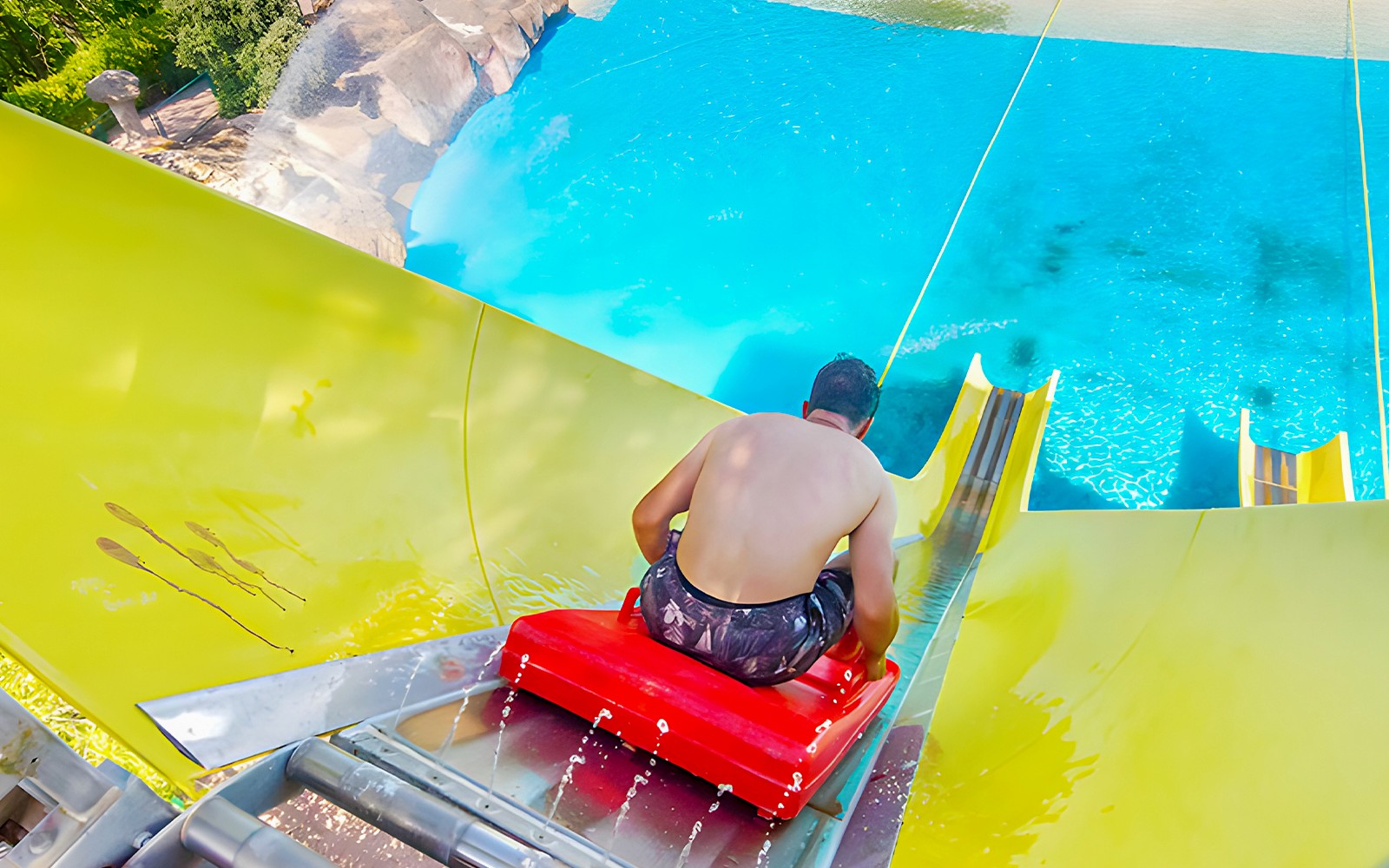 Man on a yellow water slide at Aquopolis Villanueva de la Cañada Splash.