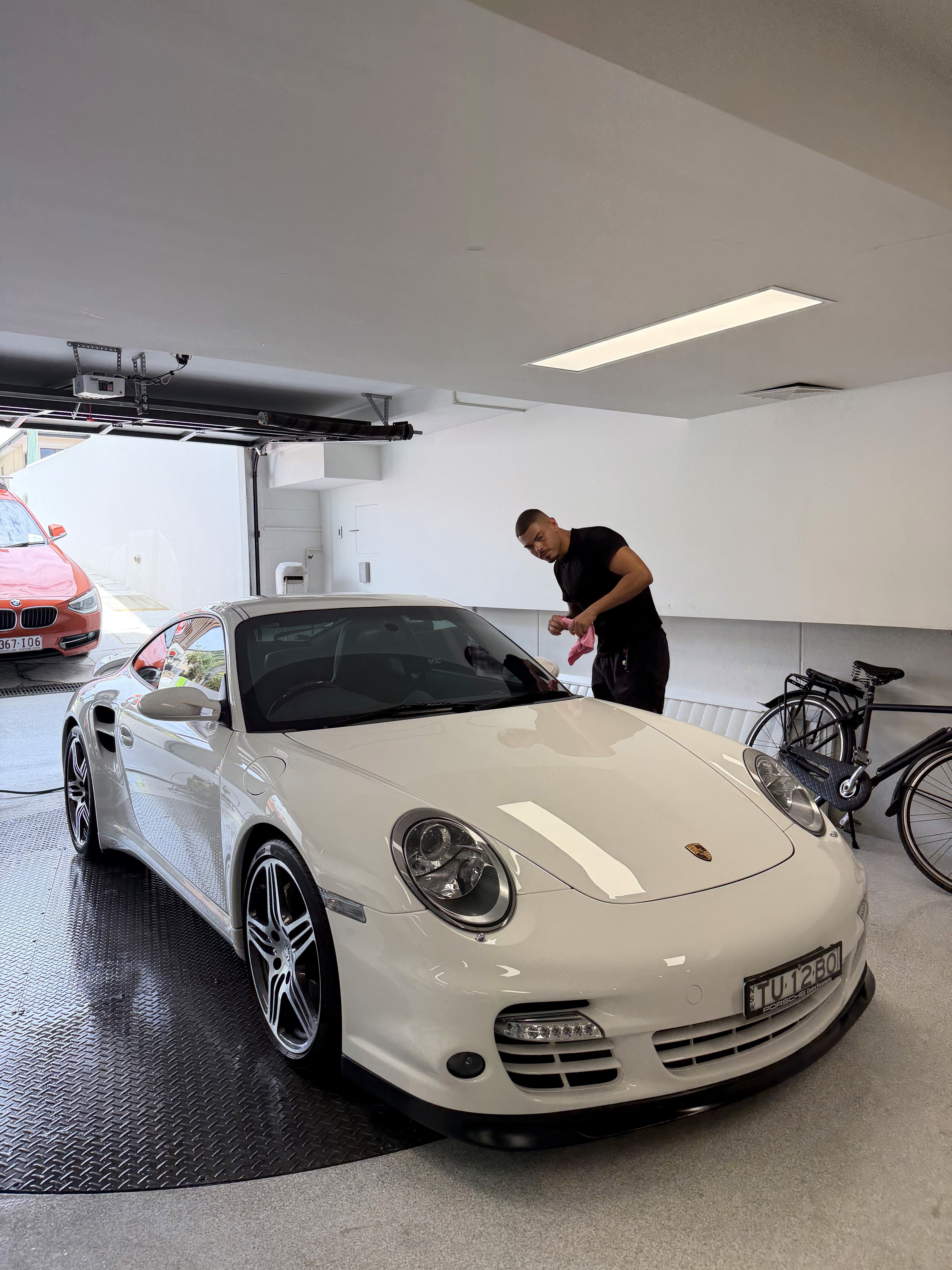 A woman lying down on a soft surface with her eyes closed, bathed in warm sunlight filtering through leaves. Her face has a natural glow, reflecting relaxation and tranquility in a serene spa-like setting.