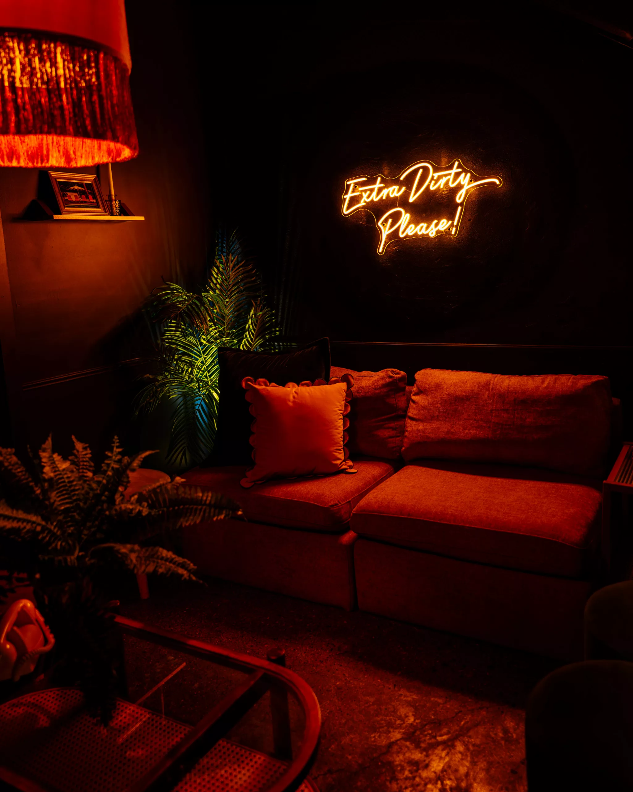 Red-lit lounge with a sofa, plants and a neon sign in Marmont at Forno Speakeasy, Forno Kitchen + Bar