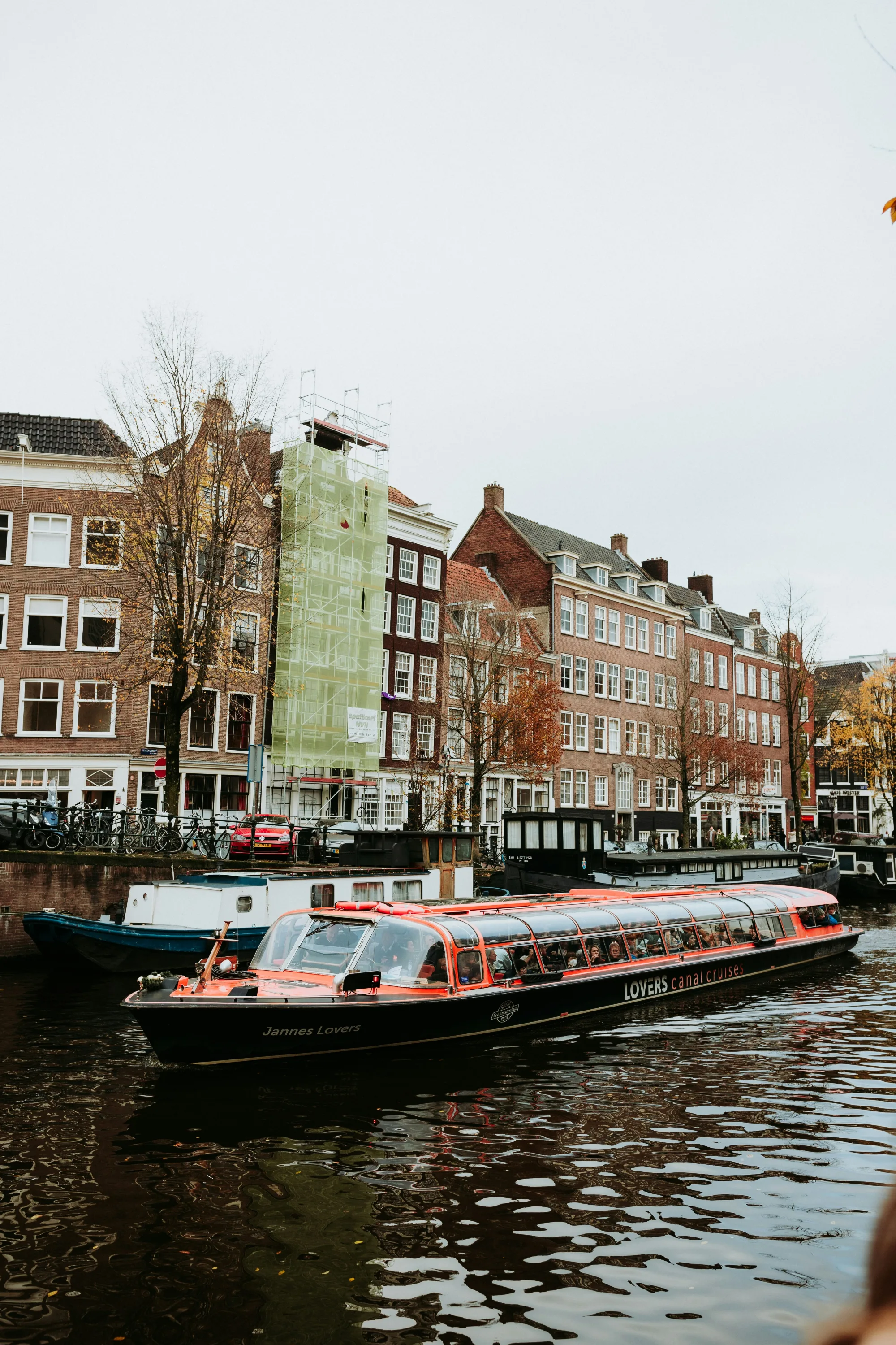 Tour boat on Amsterdam canal with traditional Dutch houses lining the water.