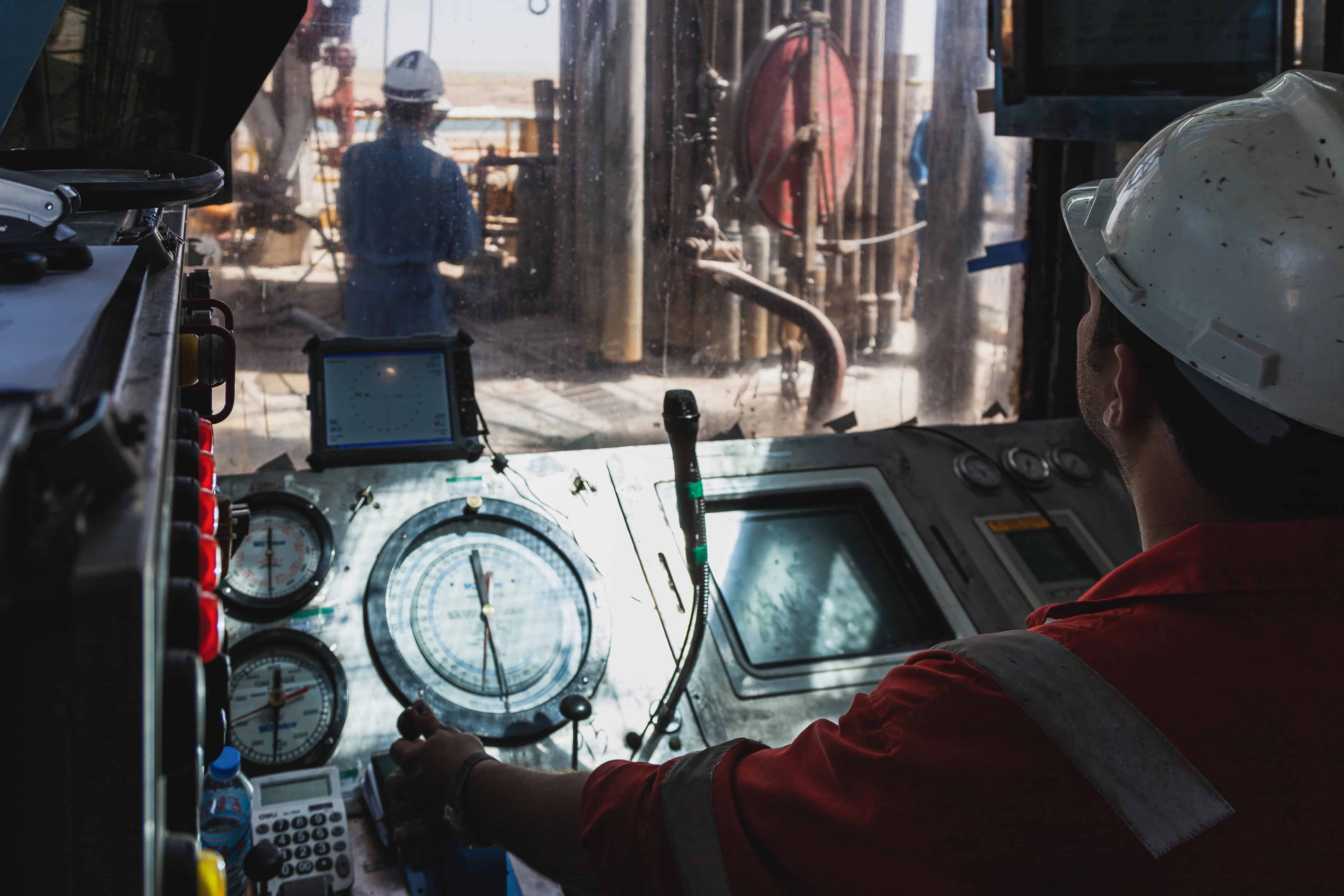 Driller observing workers on drill floor including contractors from technical services company