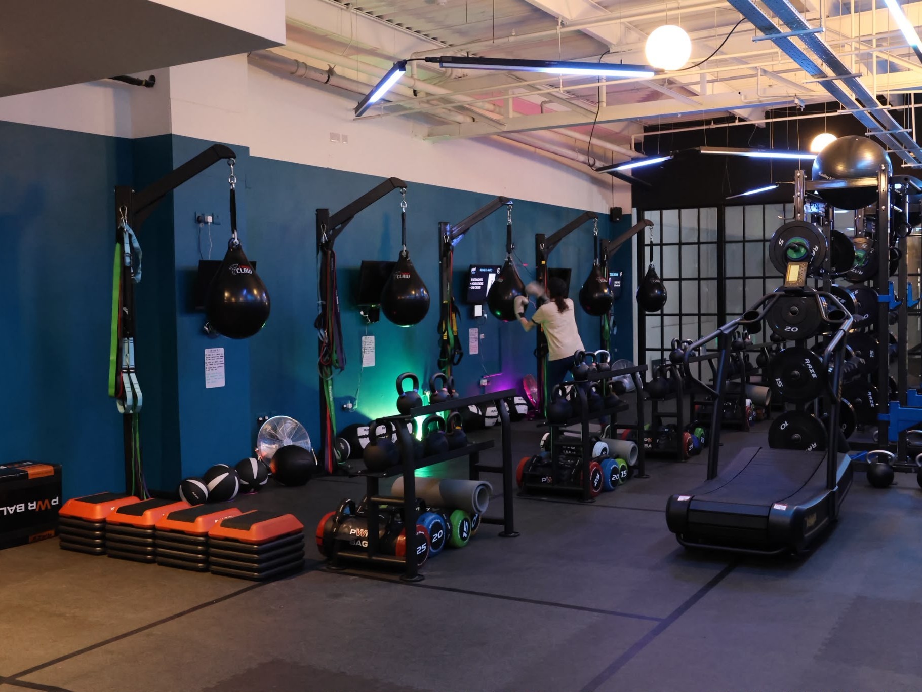 The boxing stations and kettlebell racks at MegaBox Fitness, with a member training on the bags