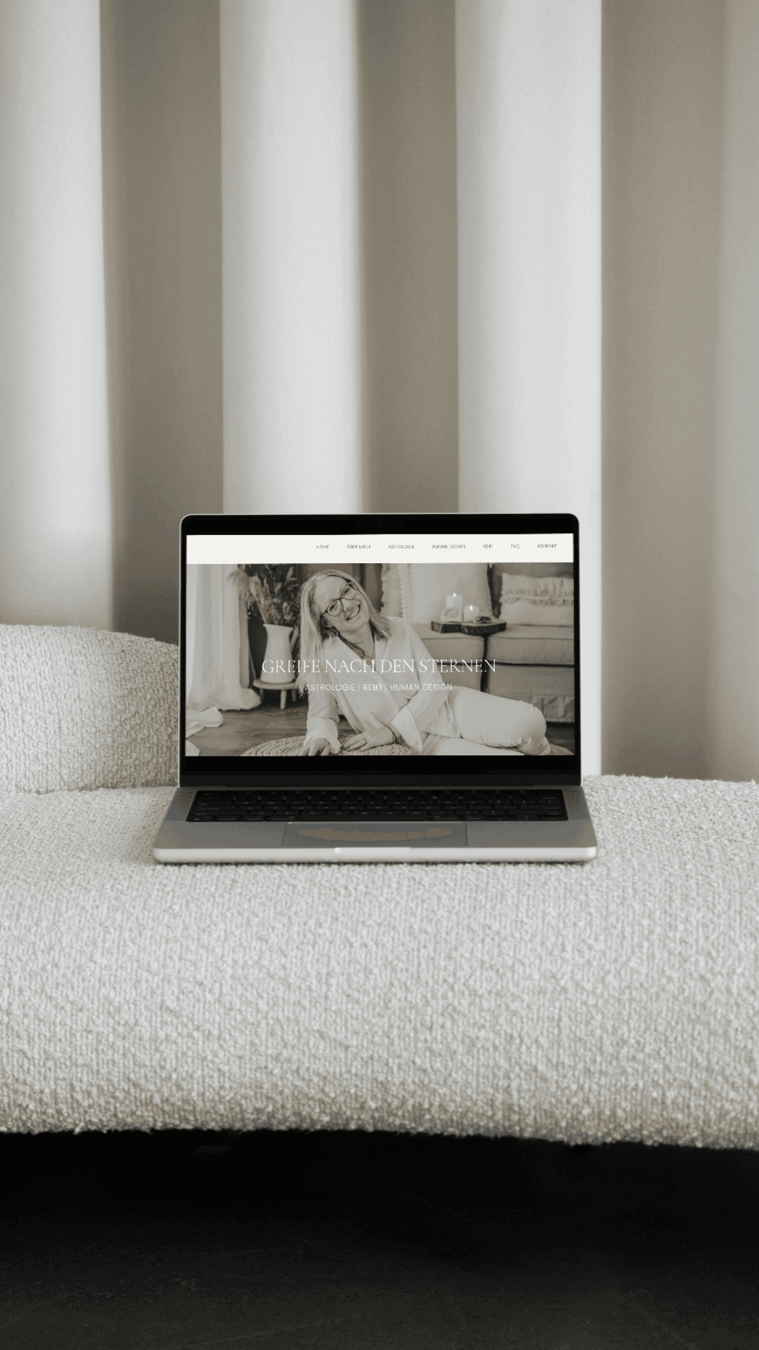 Laptop mit einer geöffneten Website von OHNORD studio designed, auf einem weißen Sofa stehend, mit hellem Vorhang im Hintergrund