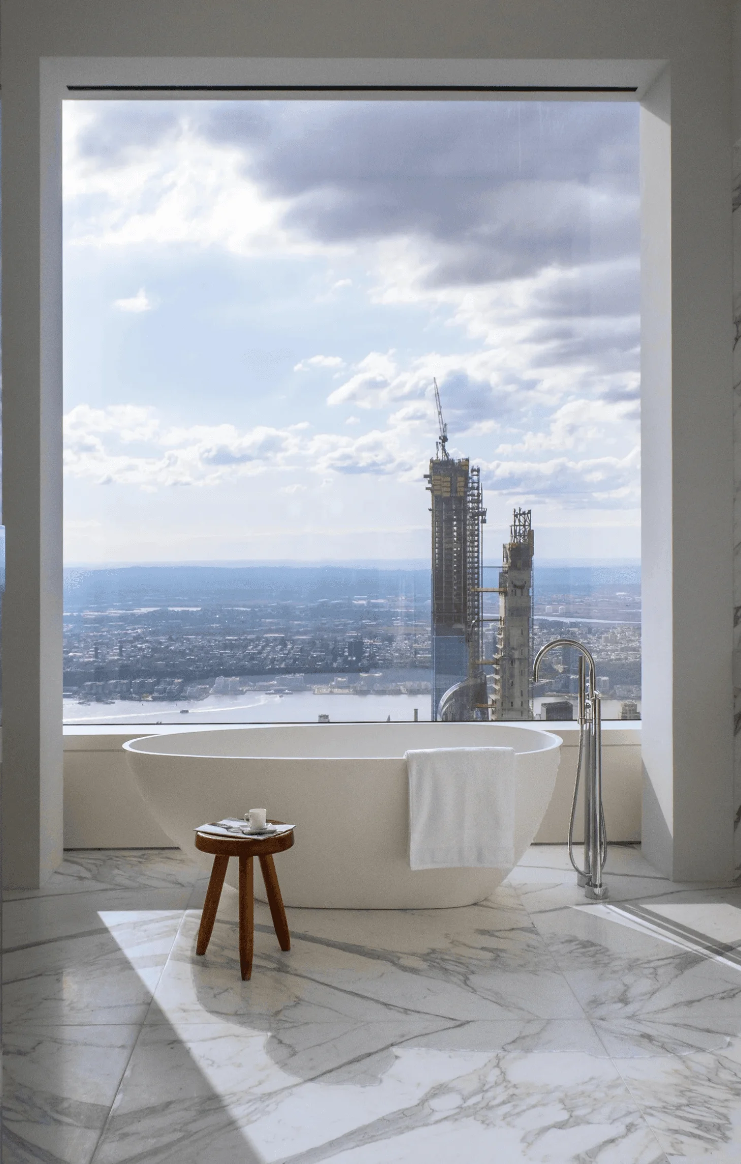 A freestanding tub and bookmatched marble floor give this primary bathroom its spa-like calm, with city views beyond