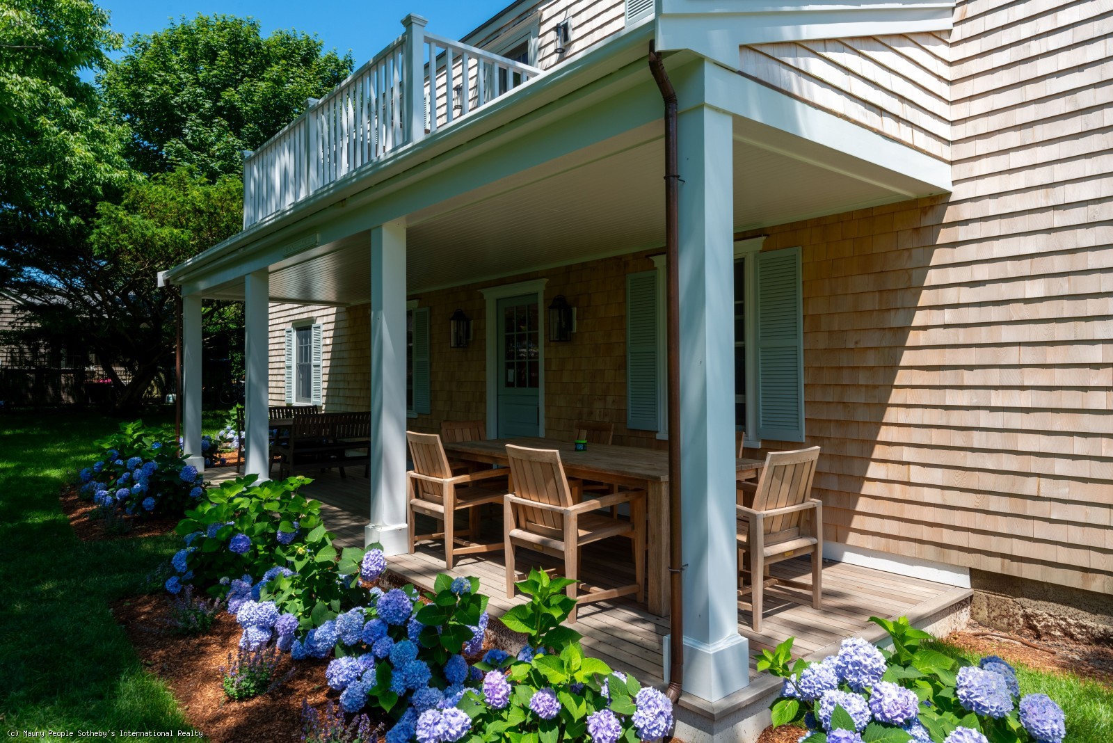View of back yard of a beautiful nantucket house with a outside table