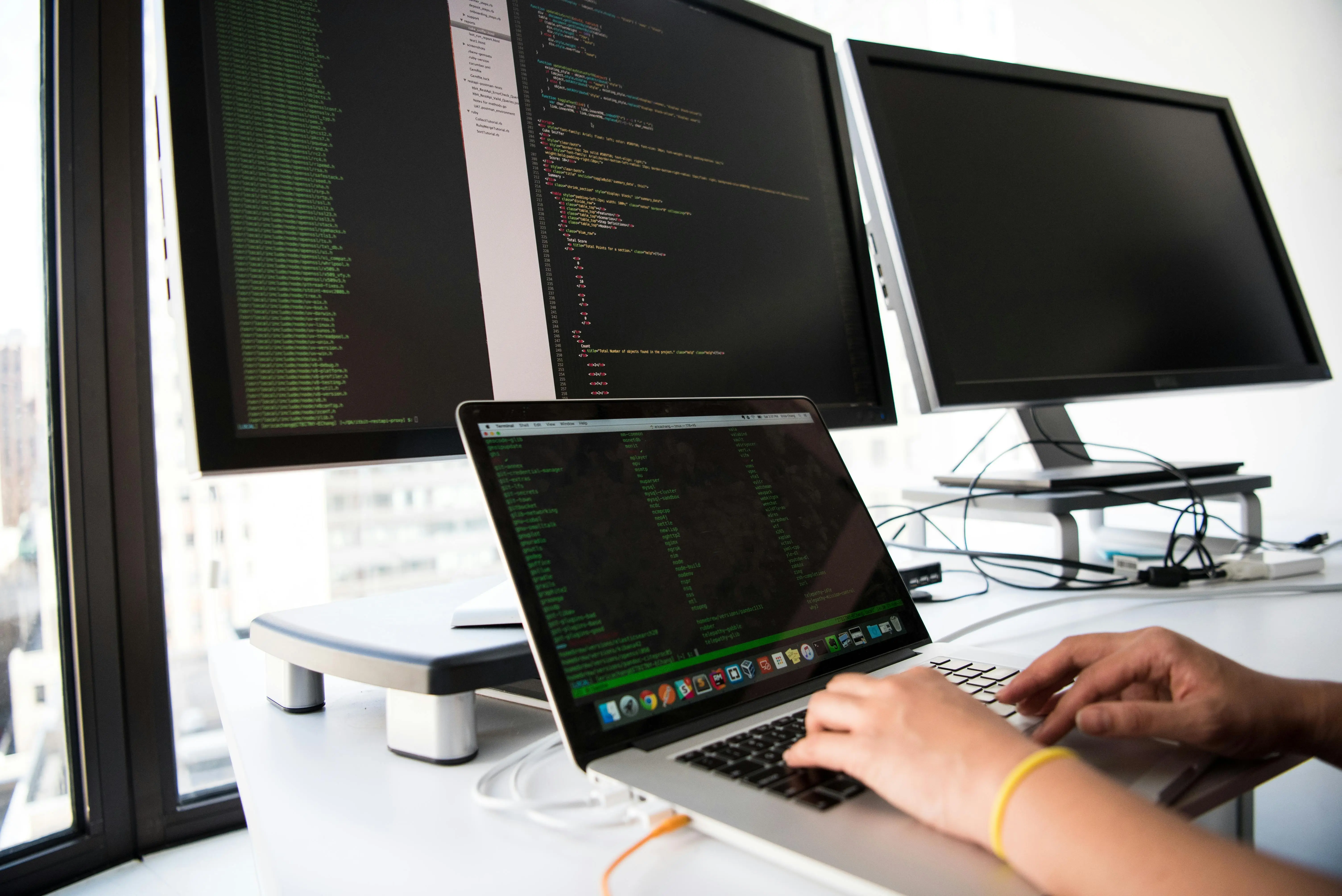 Young developer using multi-monitor setup—ideal for teenagers starting projects on coding platforms for college applications or summer STEM programs.