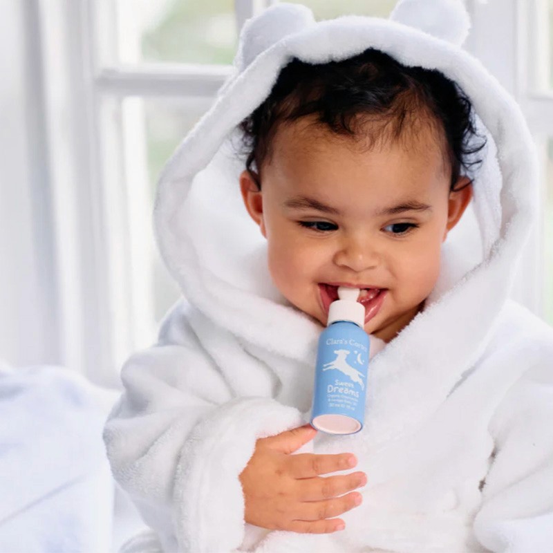 A lifestyle image showing Clara's Corner Sweet Dreams organic oil in a blue 30ml VIVOMER dropper bottle. The durable plastic-free bulb demonstrates incredible resilience and non-toxic safety for family-oriented products.