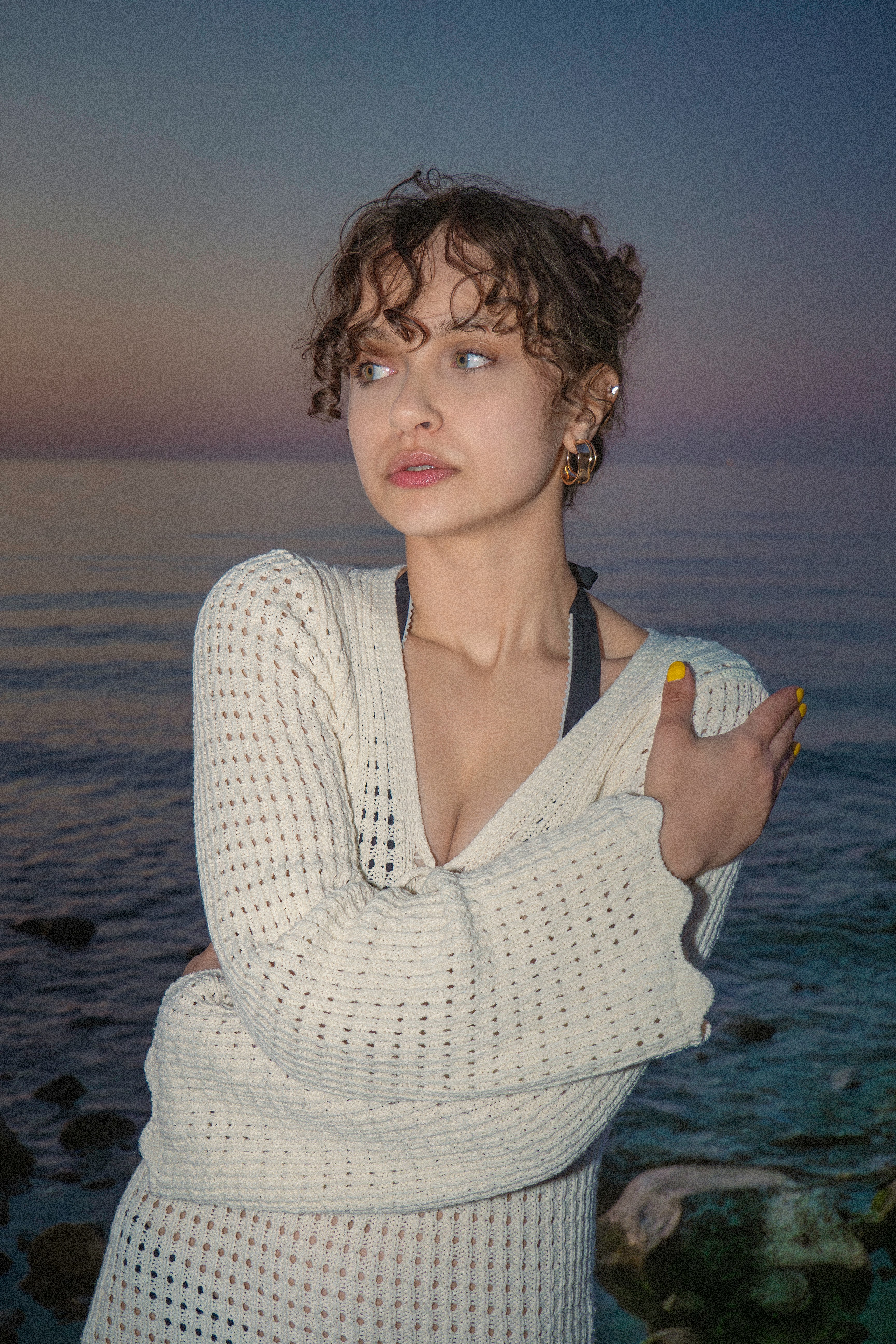 a woman standing on a beach with a cigarette in her hand