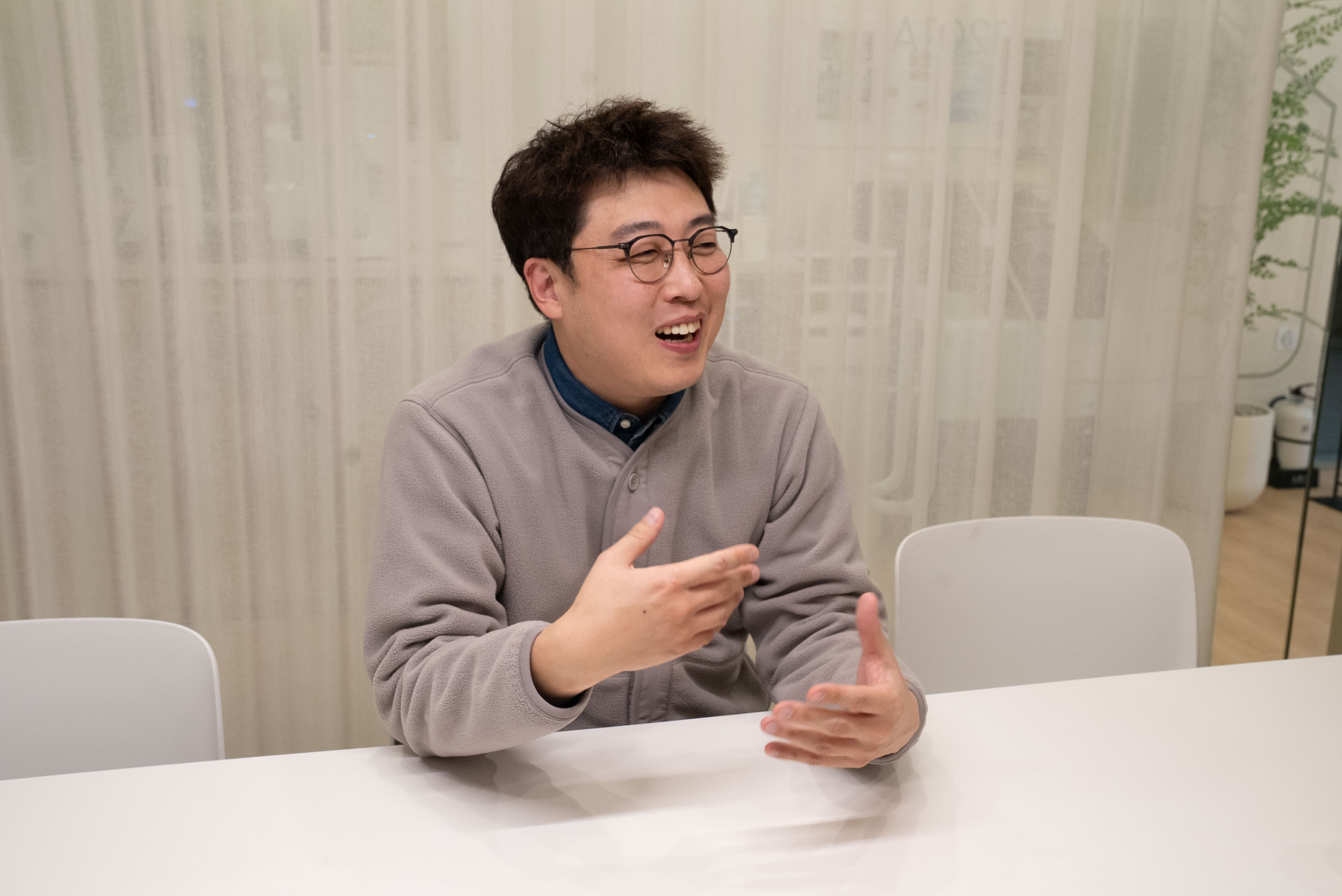 두 손을 들어 제스처를 취하며 밝게 웃고 이야기하는 어지환 과장의 모습입니다.