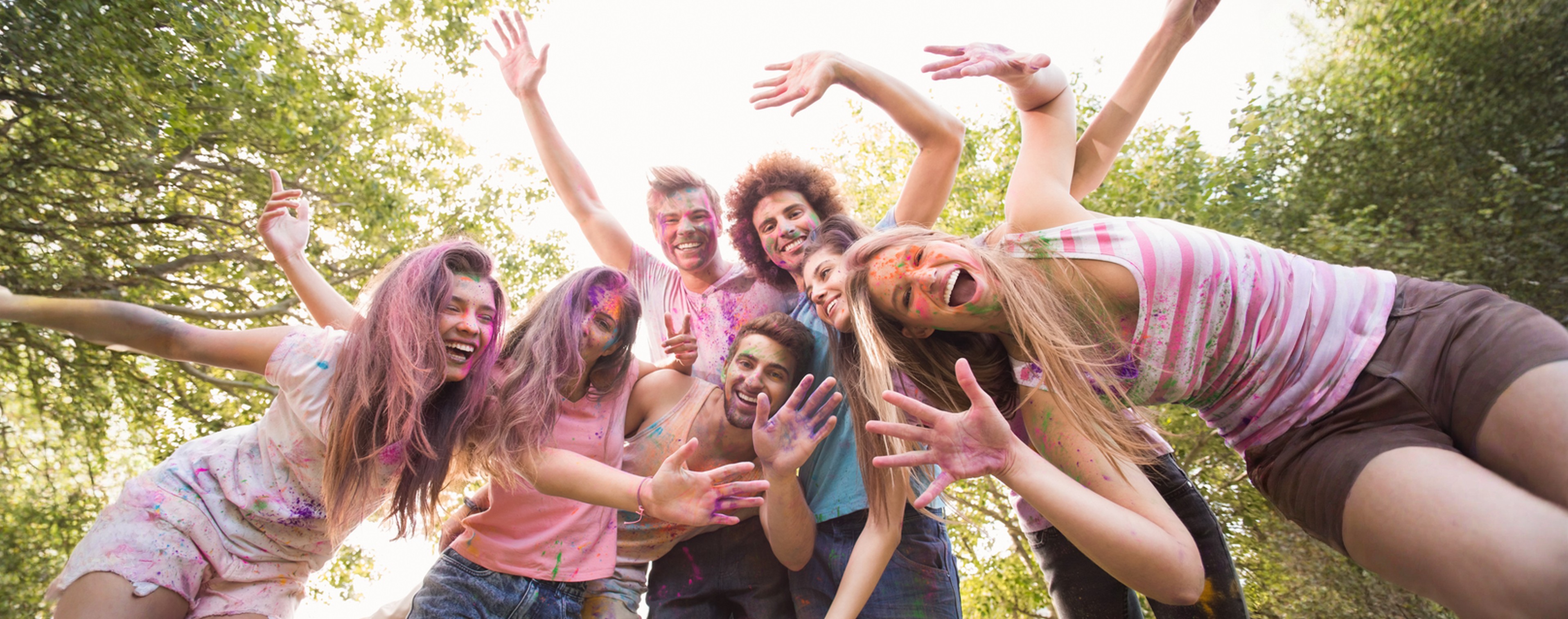 Young people with coloured dust on their faces lying on the grass enjoying each other's company