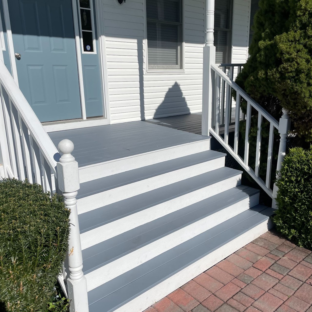 Completed gray composite front porch steps with white vinyl railings
