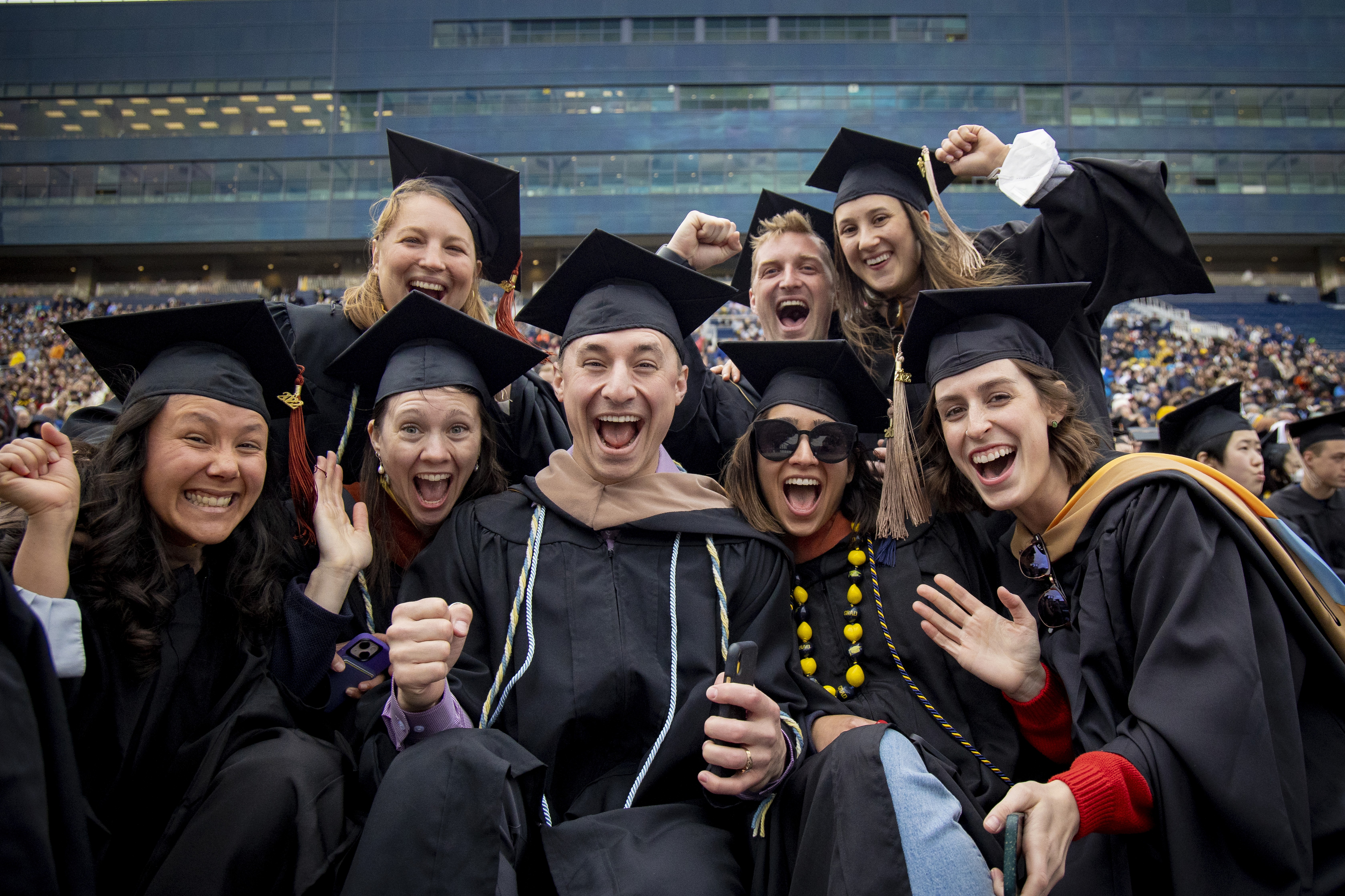 Group of smiling graduates in caps and gowns celebrating together.