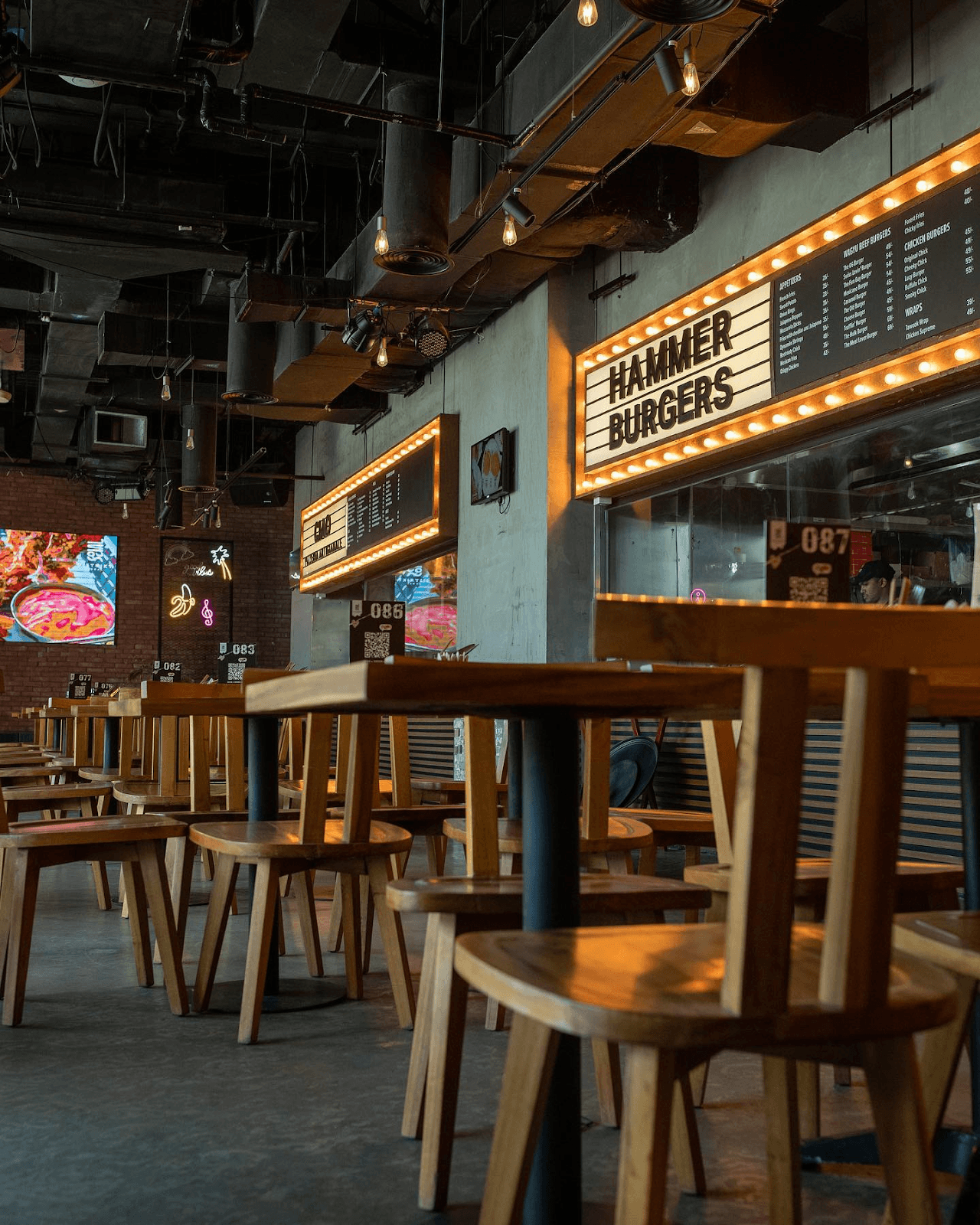 Food vendor stalls and communal seating inside a modern social restaurant food hall.