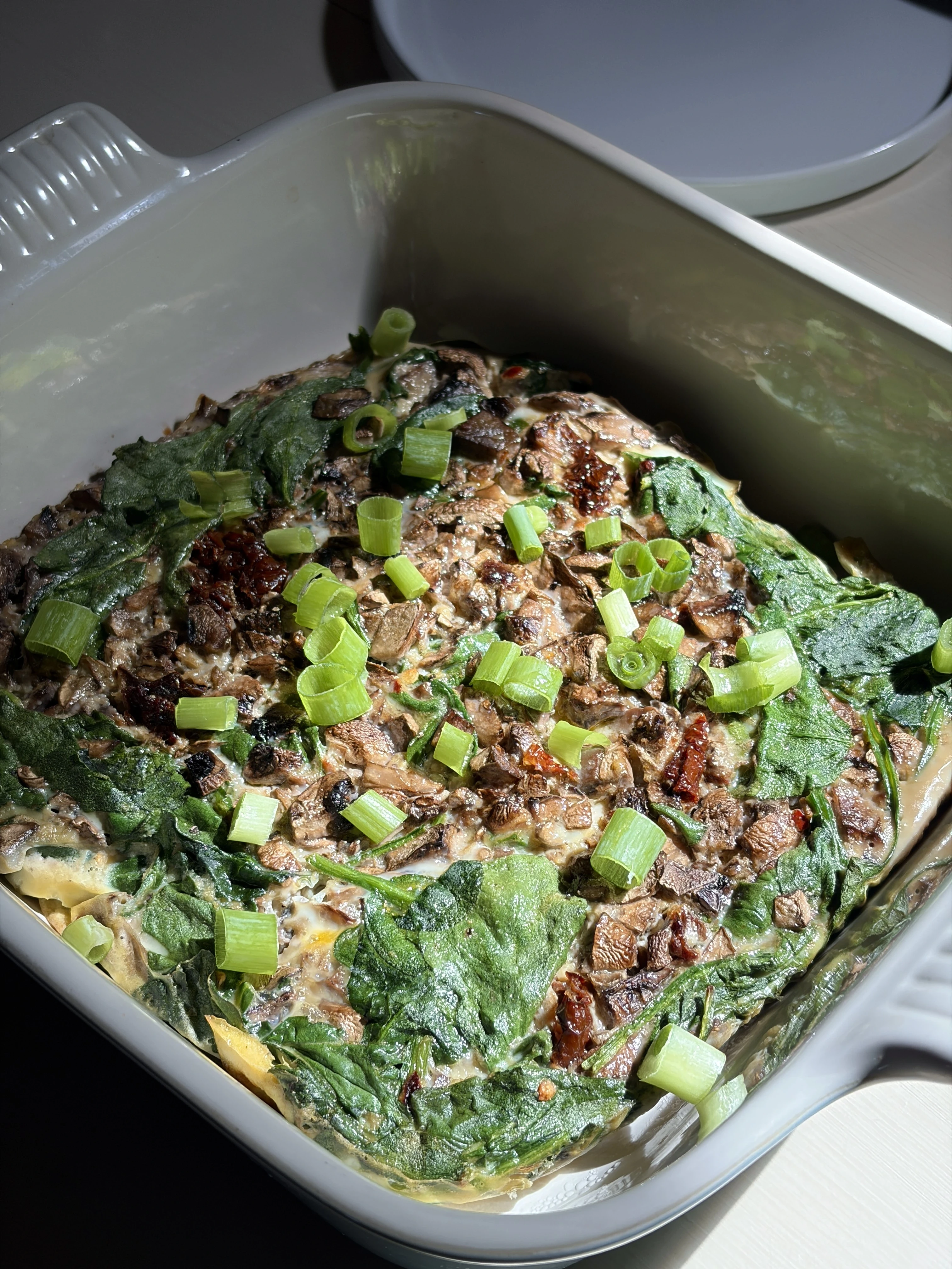 Sun-dried tomato spinach egg bake with green onions on top for a nourishing and delicious breakfast