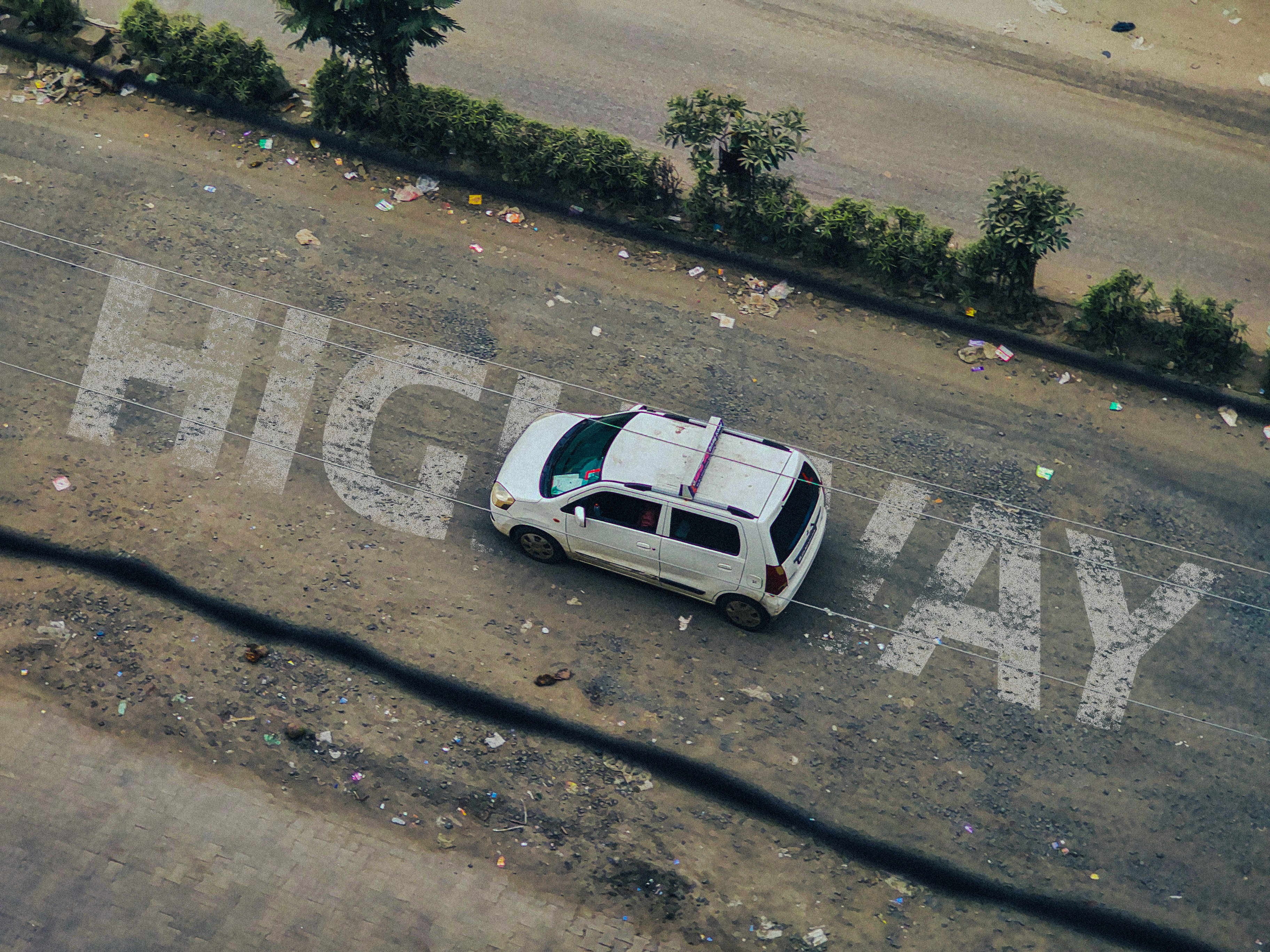 Automotive photography of a white car on a city road marked with highway lettering, composed by Samuel Singh Bhakuni.