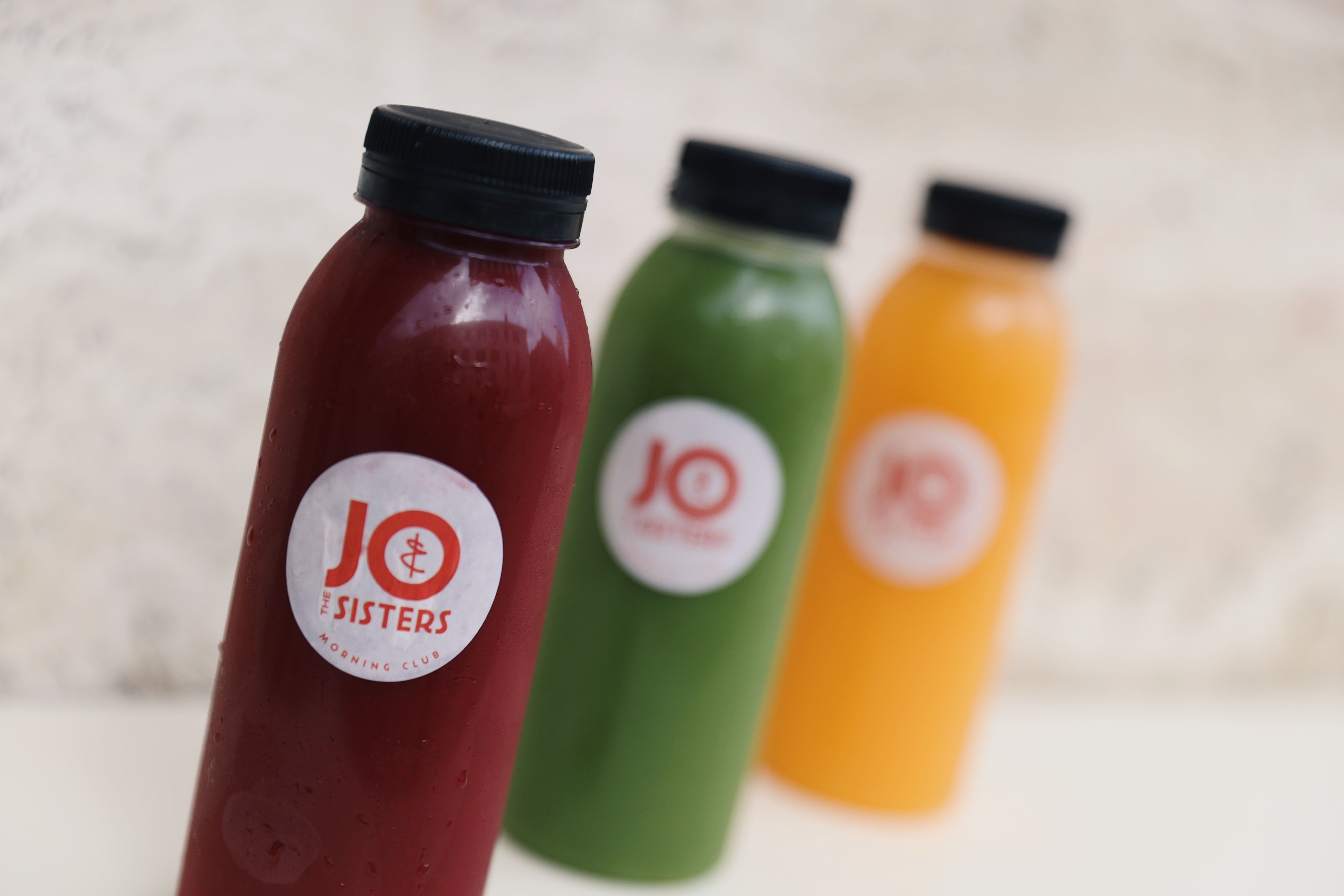Colorful cold-pressed juice bottles from Jo & The Sisters featuring Red Revive, Green Goddess, and Sunshine Squeeze