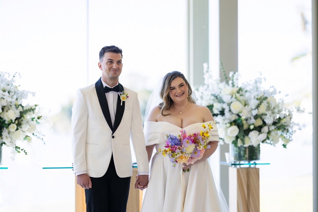 Bride and groom standing in church smiling at the audience