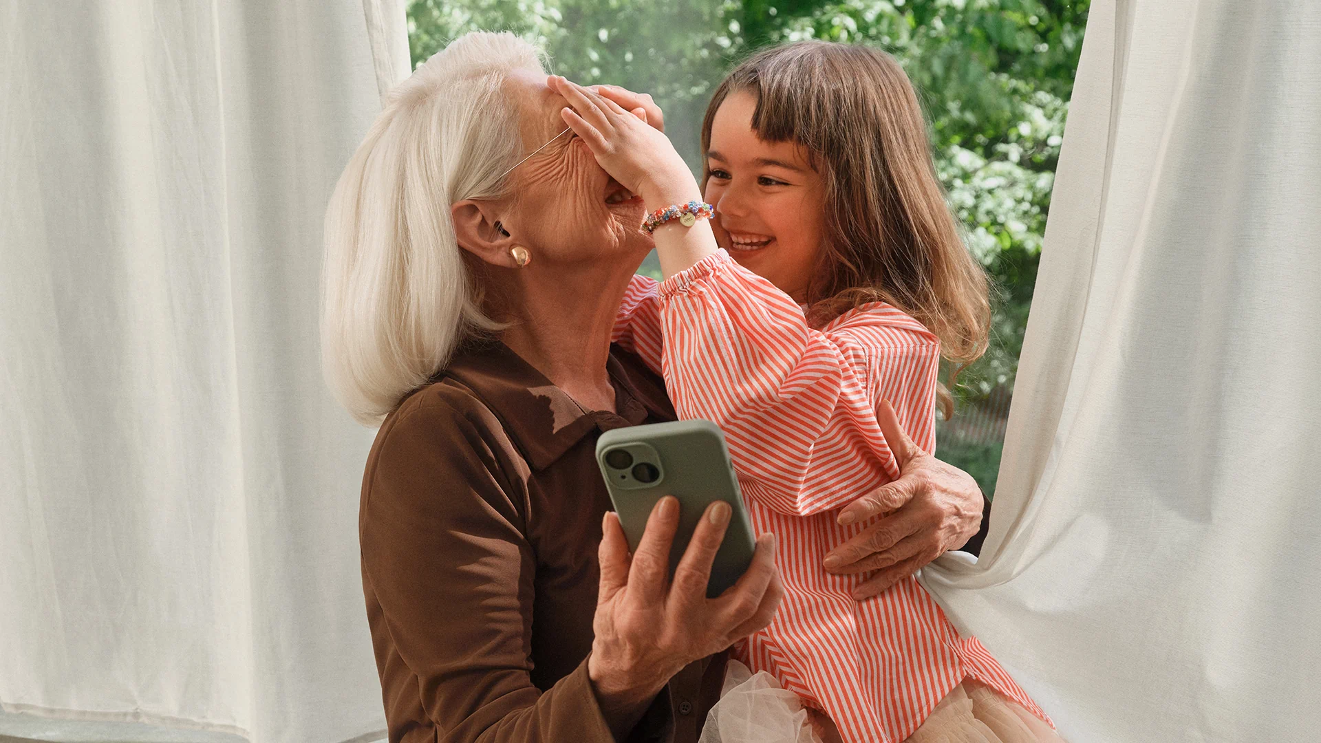 Grandmother and granddaughter sharing a joyful moment in Fielmann’s hearing care campaign.