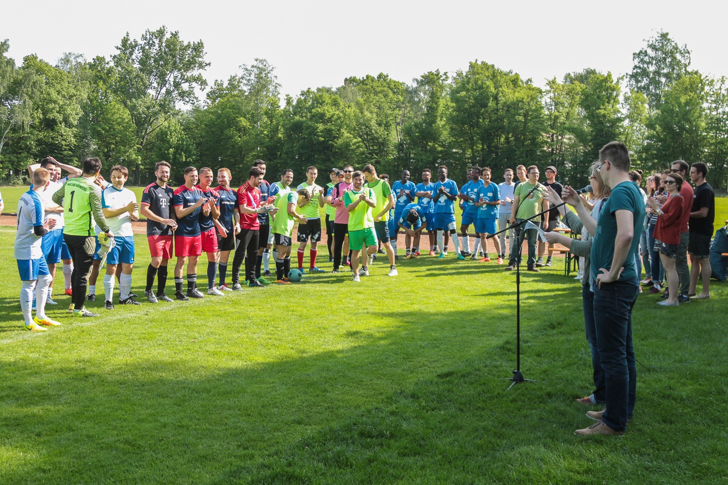 Verbandmitglieder stehen gemeinsam in einem sonnigen Tal, umgeben von einer offenen Landschaft und hellem Tageslicht.