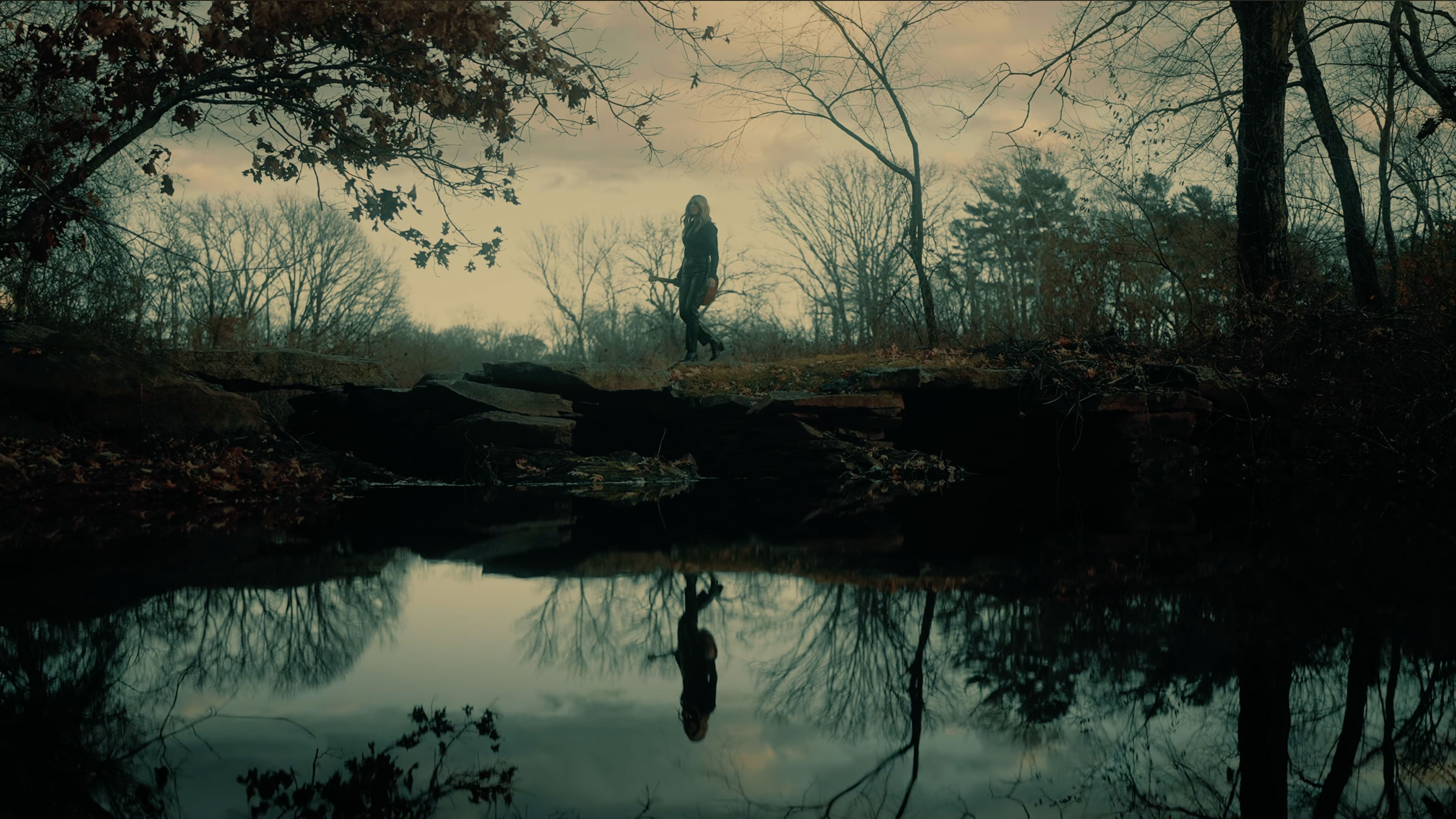 Person walking across Skim Milk Bridge above the Town River in West Bridgewater, Massachusetts, reflected in the water below.