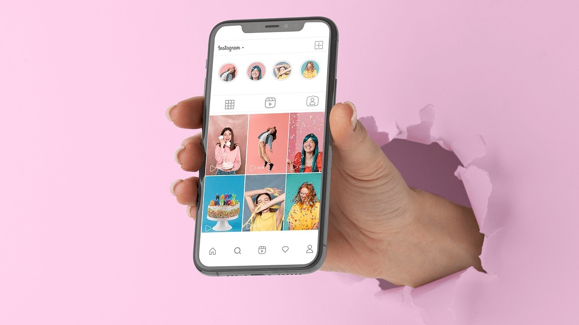 a hand breaking the pink papper while holding a cell phone showing Instagram feed UI