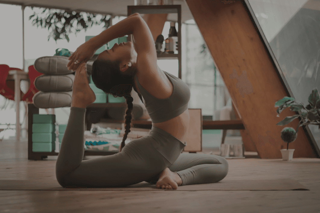 Woman practicing yoga indoors in a bright wooden room.