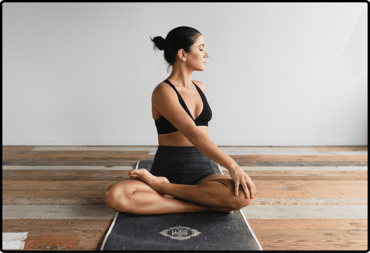 A woman sitting on a yoga mat while wearing workout clothing