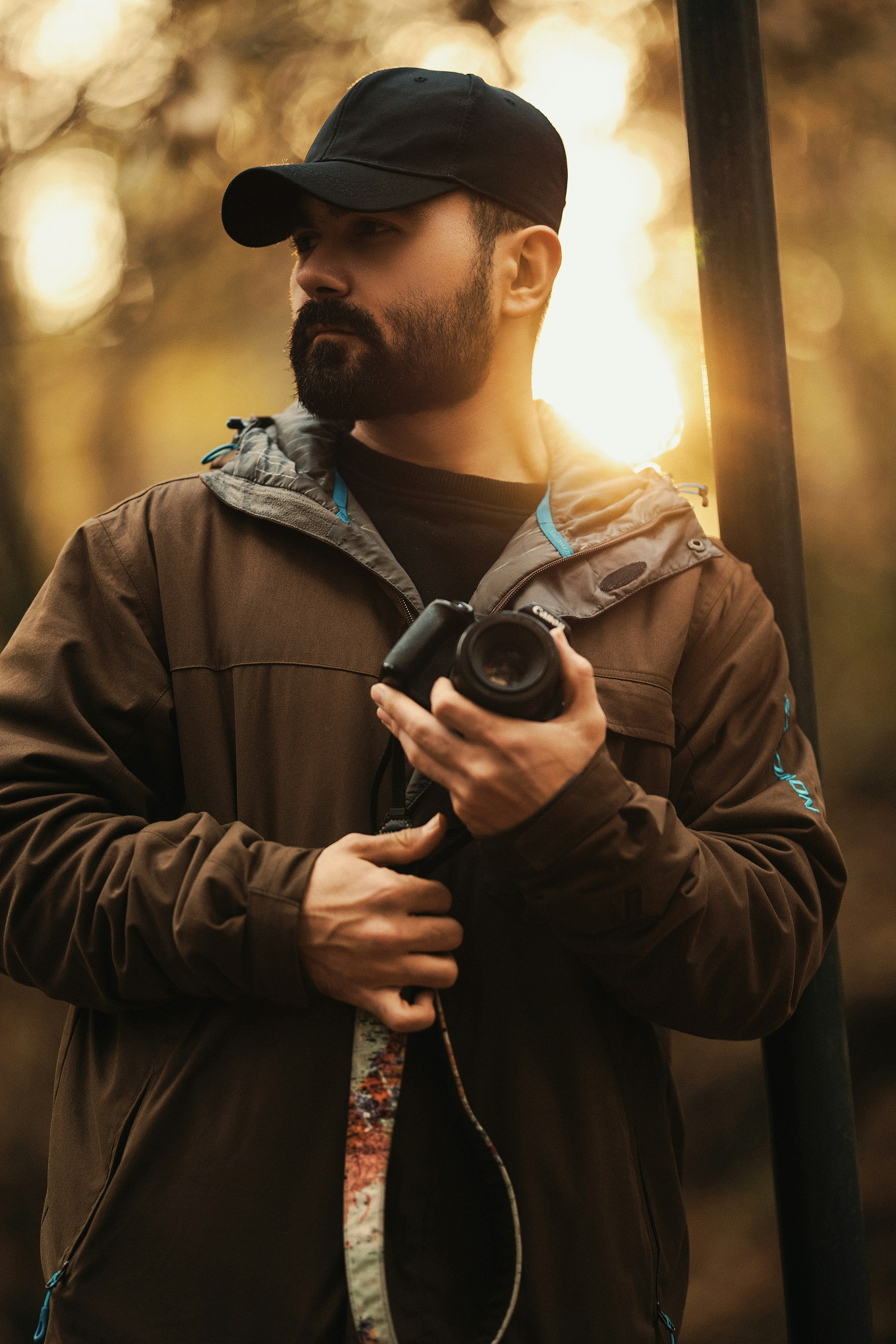 A man holding a camera while standing next to a pole