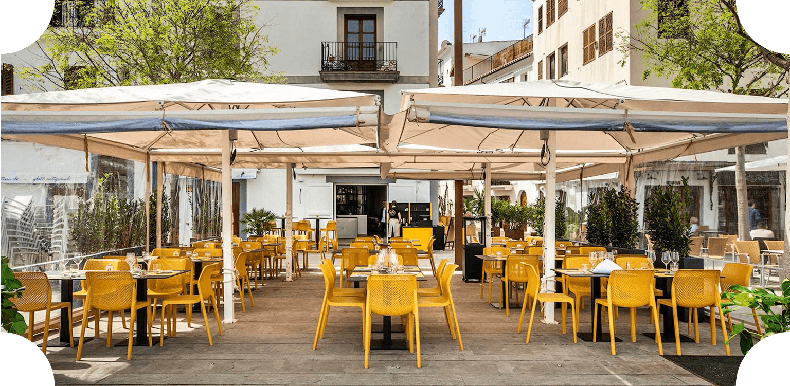 Terraza exterior de Casa Francesco con sillas amarillas y mesas bajo grandes toldos color crema.