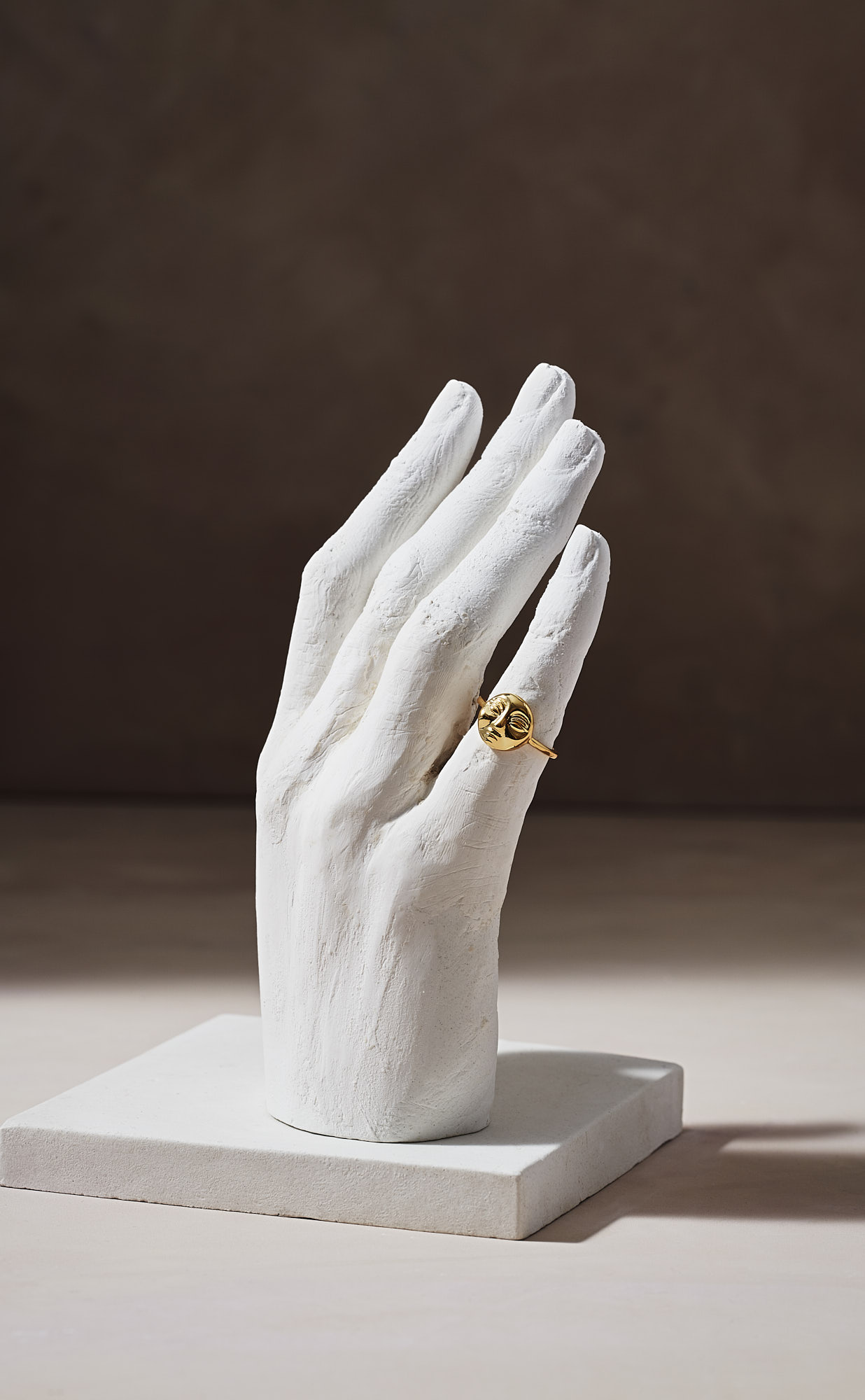 Gold ring on white plaster hand sculpture display.