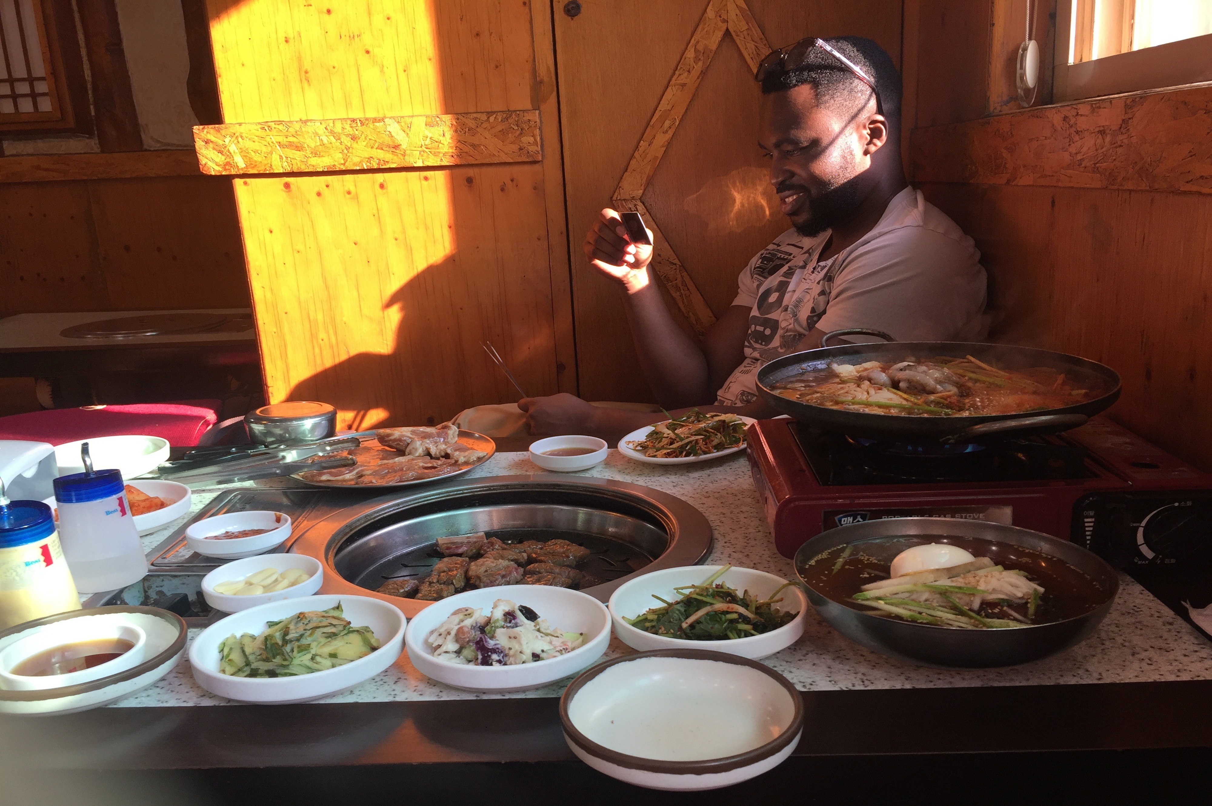 man sitting on floor surrounded by Korean food