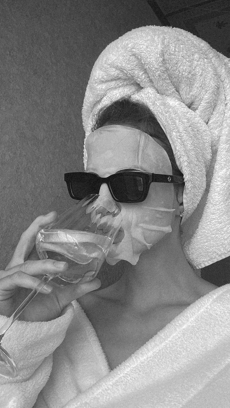 A stylish woman in a brown coat and white turtleneck, accessorized with elegant earrings, against a neutral background.