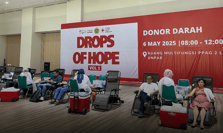 person in gray hoodie holding red and white box