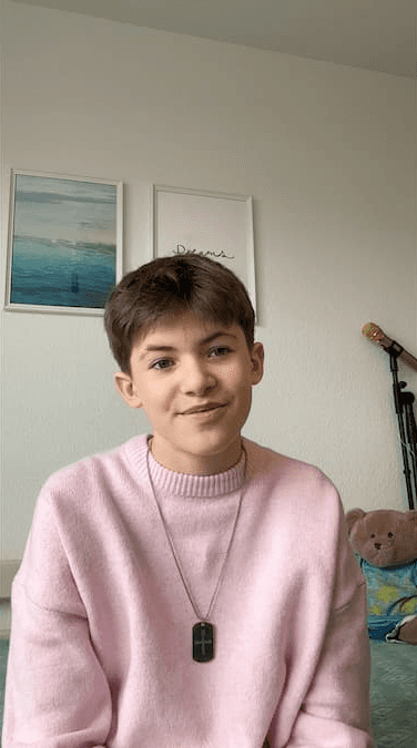 Marius steht strahlend vor dem Plakat des Musicals Billy Elliot in Zürich. Er wurde im Projekt Coaching von Danielle Zuber auf seine Musical-Rolle vorbereitet.