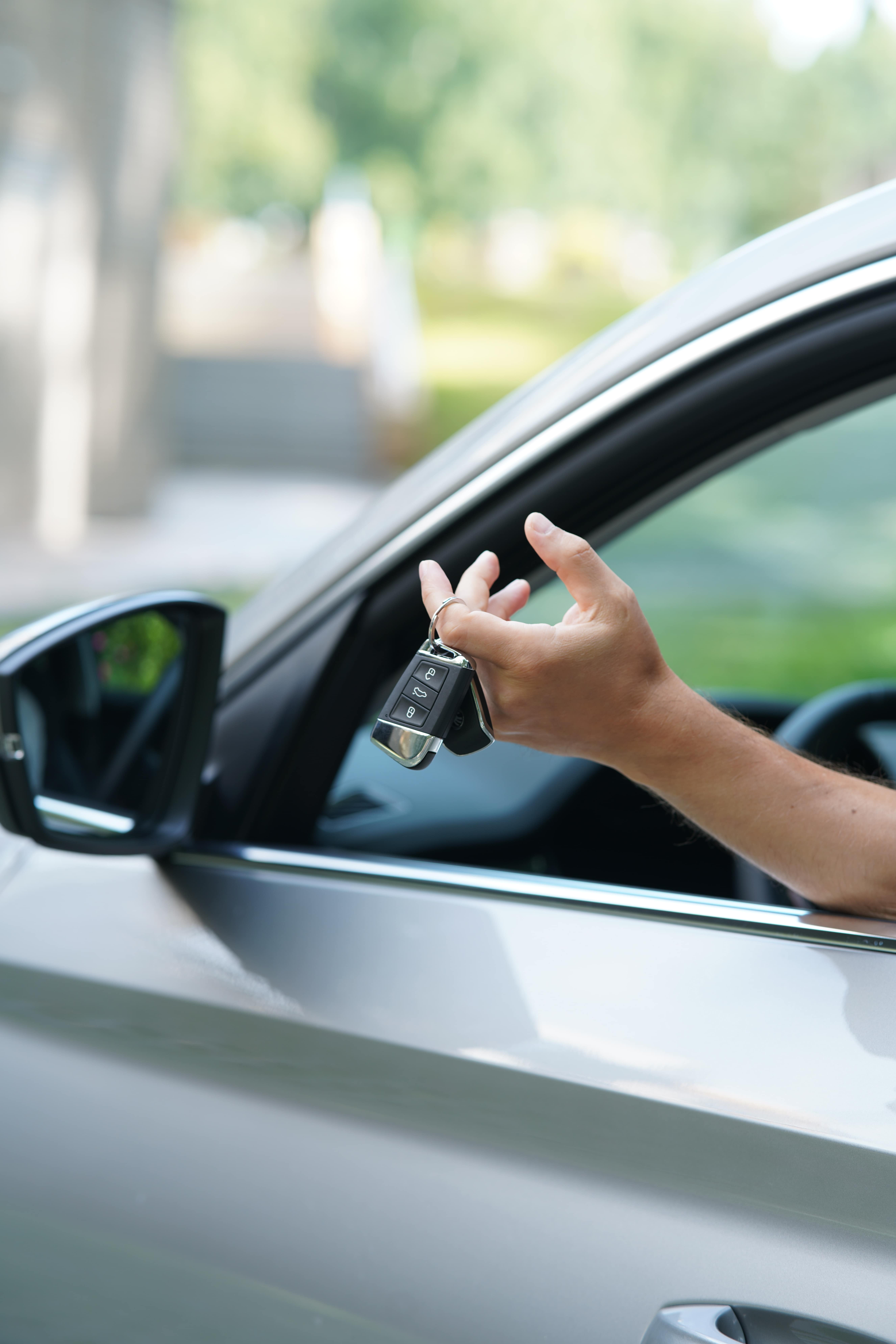 Fahrer hält Autoschlüssel aus dem Fenster – Symbol für neu gewonnene Freiheit nach erfolgreicher MPU-Vorbereitung und bestandener MPU-Prüfung.