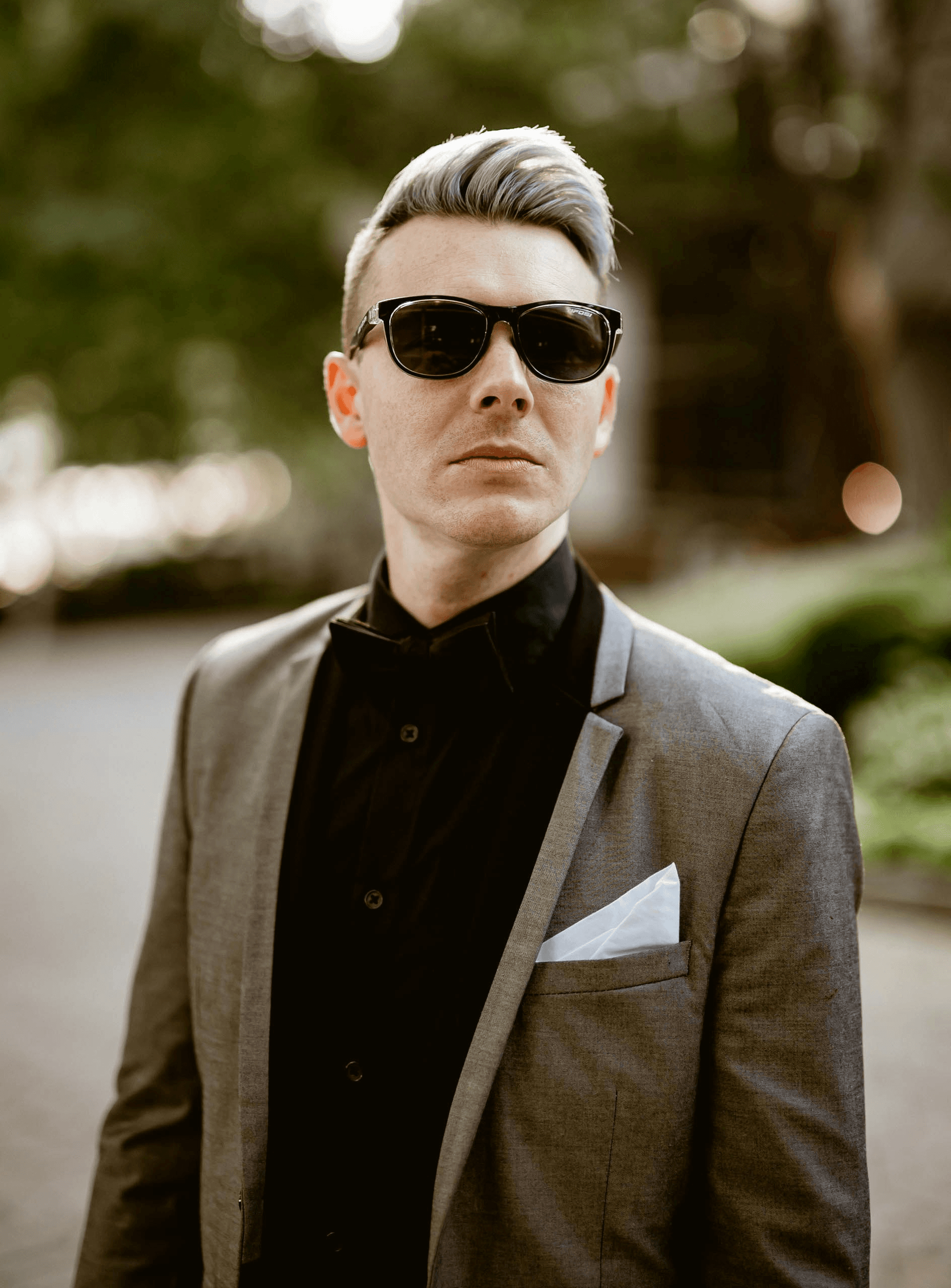 A man in a suit and sunglasses standing on a street