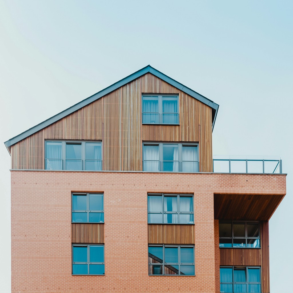 A modern building with a sloped roof, featuring large windows and a mix of wood and orange exterior.
