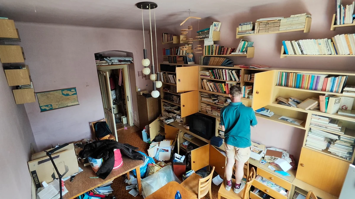 Pokoj s knihovnami a stolem před odvozem nábytku